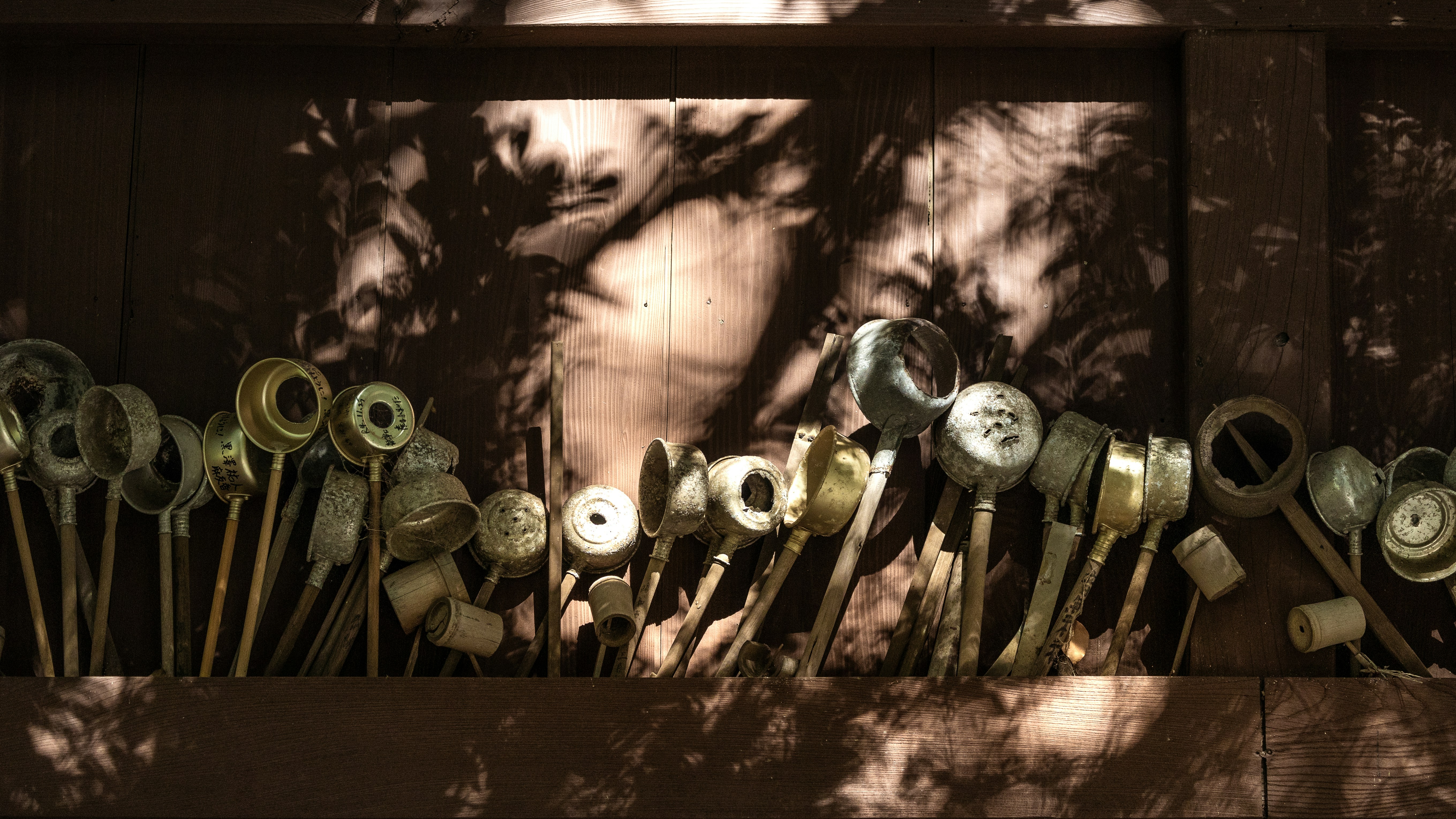Row of metal ladles against a shadowed wall