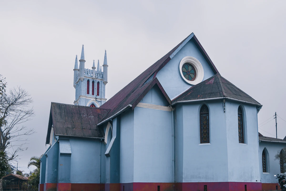 The pale blue Gothic walls, rose window and pinnacled tower of Macfarlane Memorial Church, Kalimpong