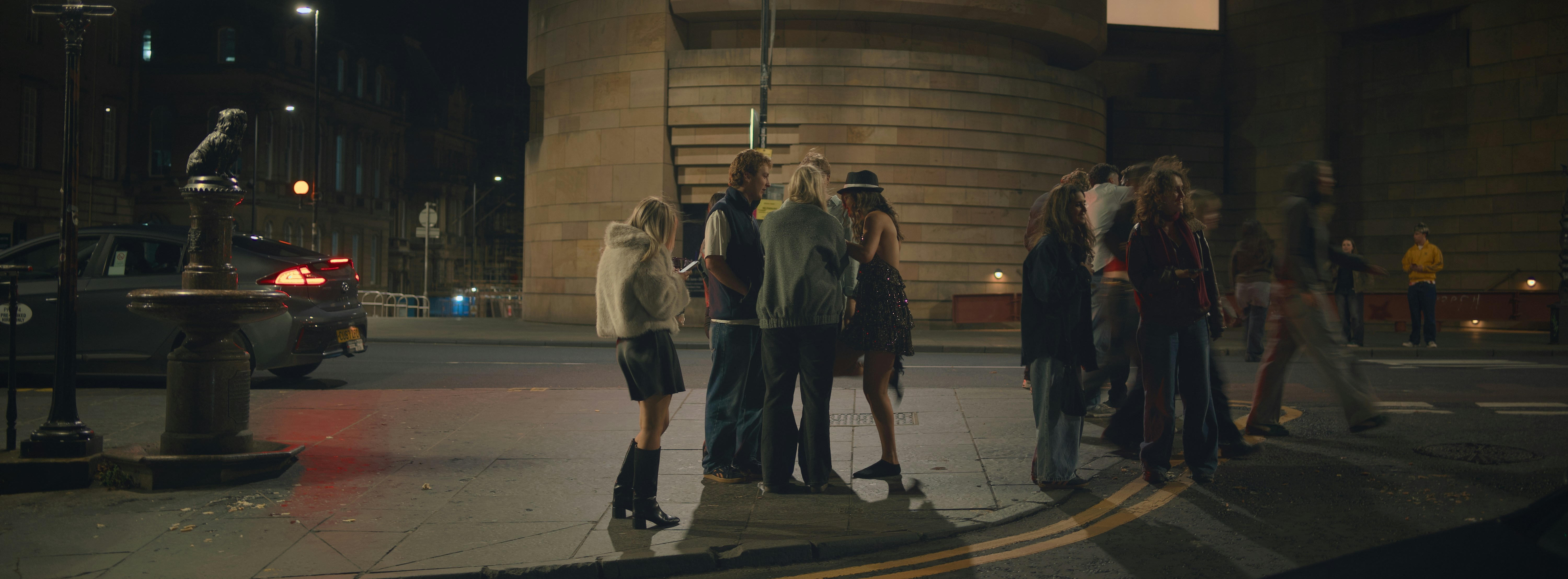 A group of people standing on a street at night.