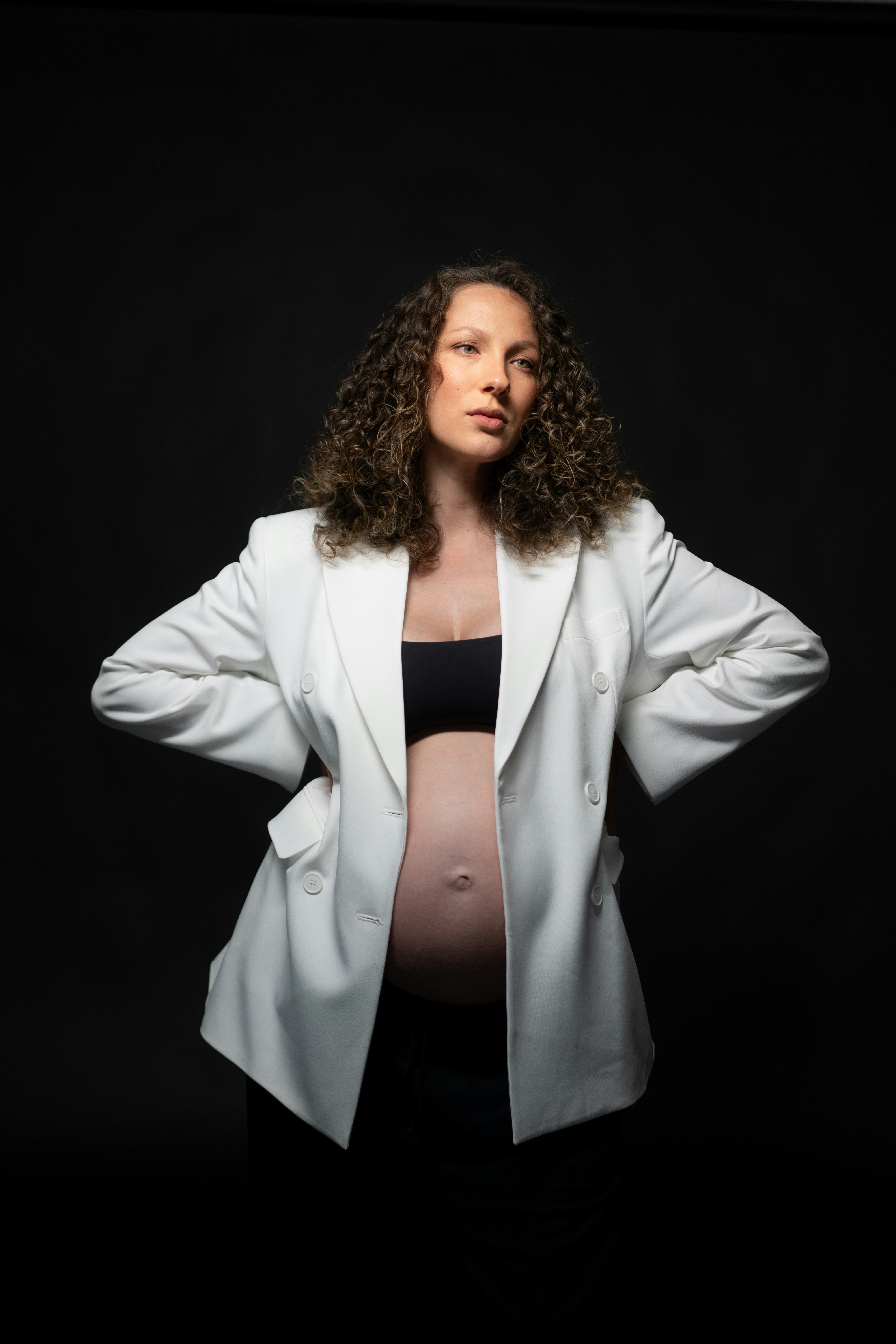 Donna incinta con giacca bianca su sfondo nero