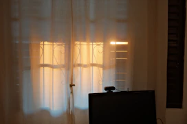 Sunlight shines through sheer curtains onto windows.