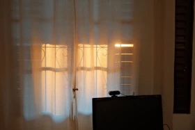 Sunlight shines through sheer curtains onto windows.