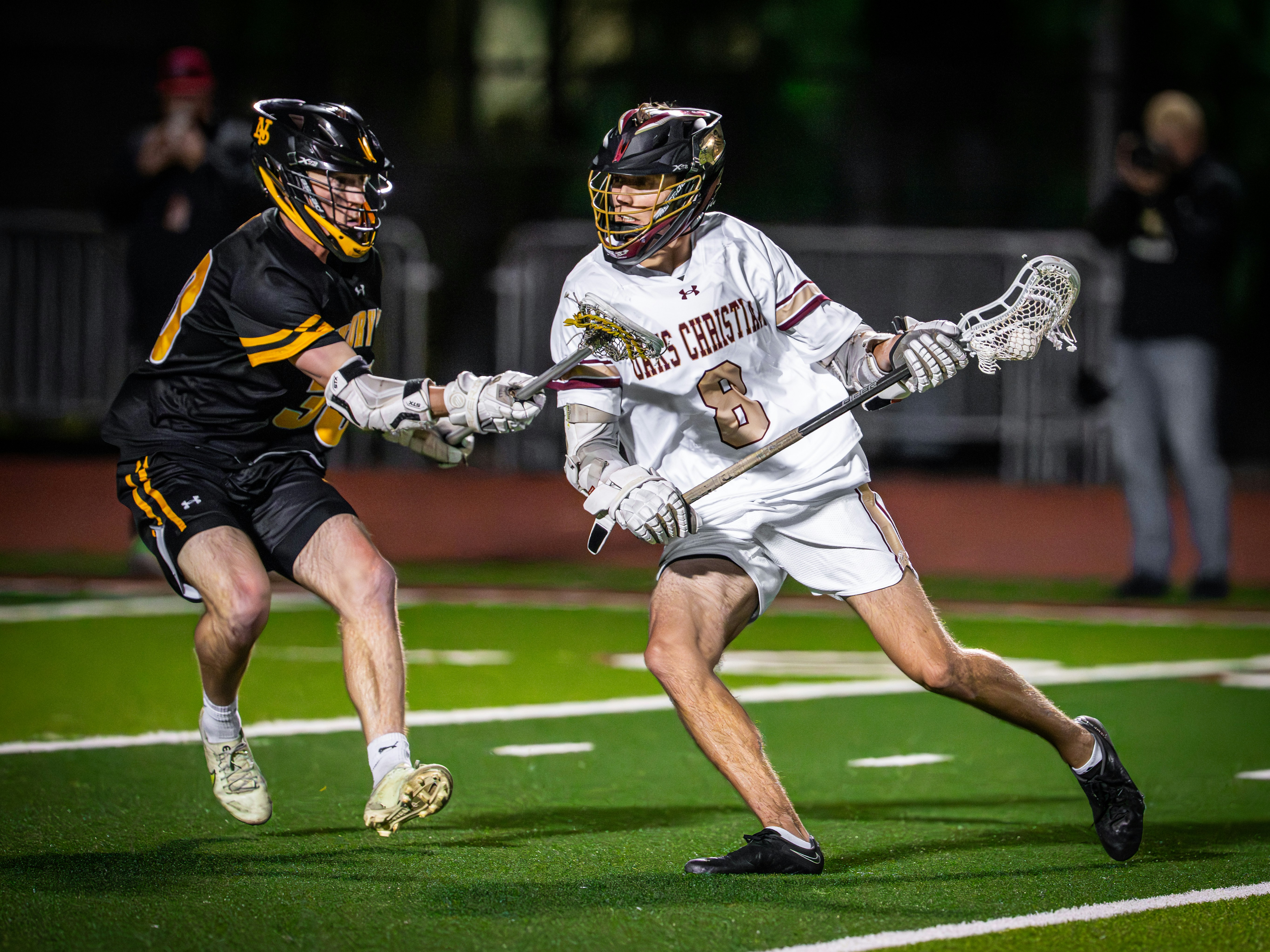 Two lacrosse players competing for the ball on a field.