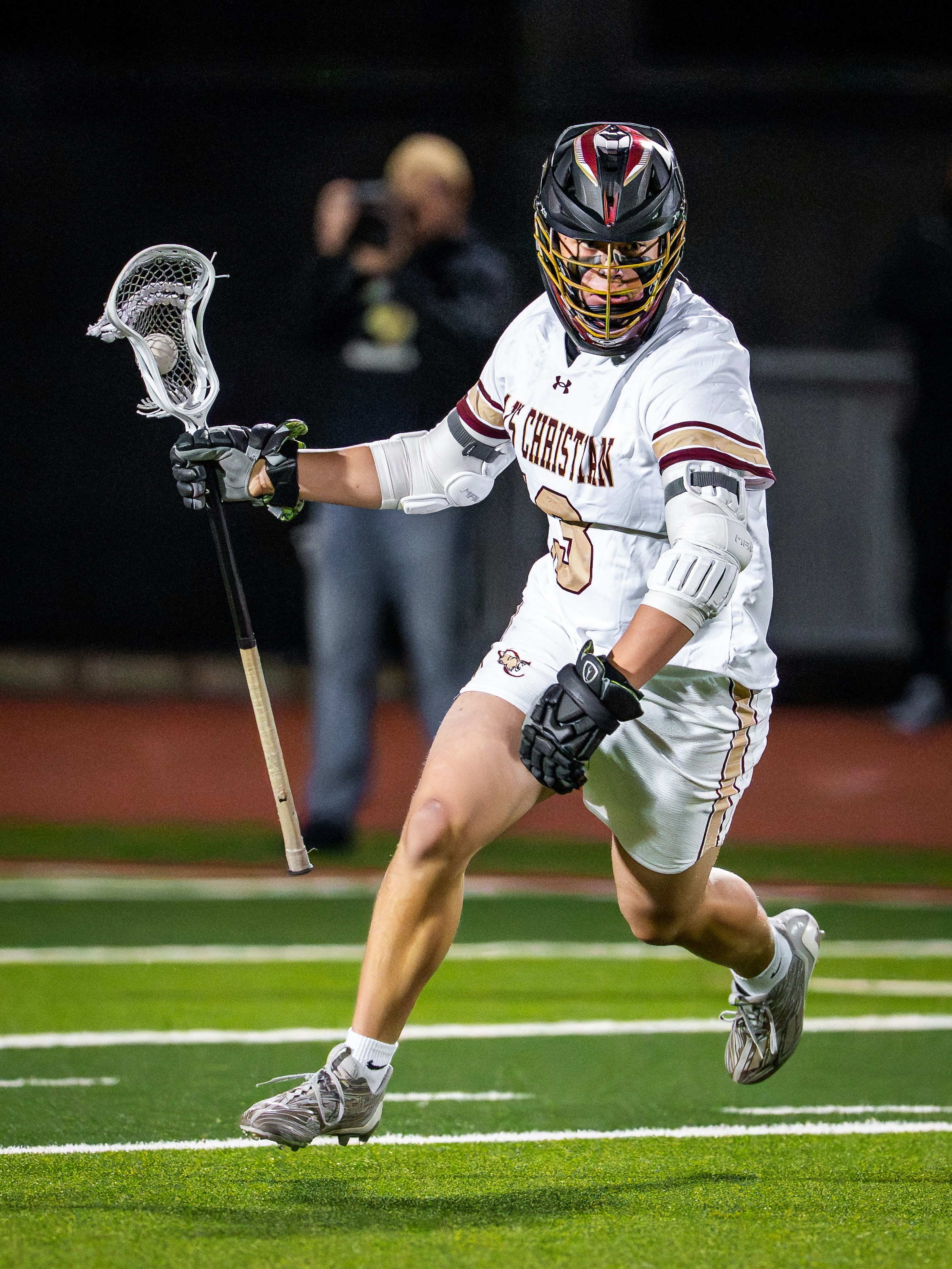 Lacrosse player in uniform running on field