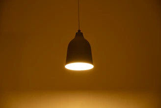 A single pendant light illuminates a dark room.