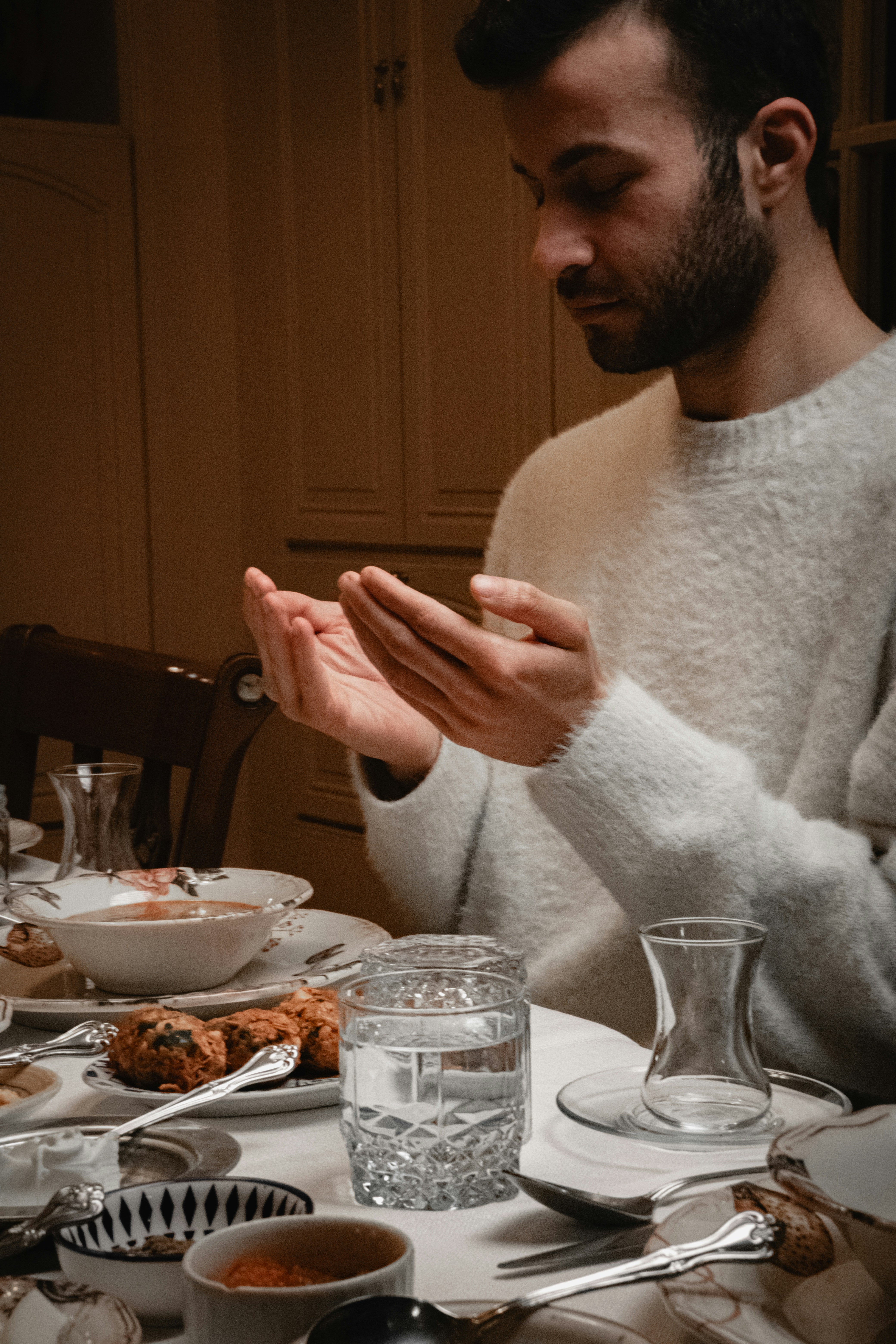 Man praying at a table set for a meal