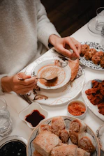 A person eating soup with bread and appetizers.