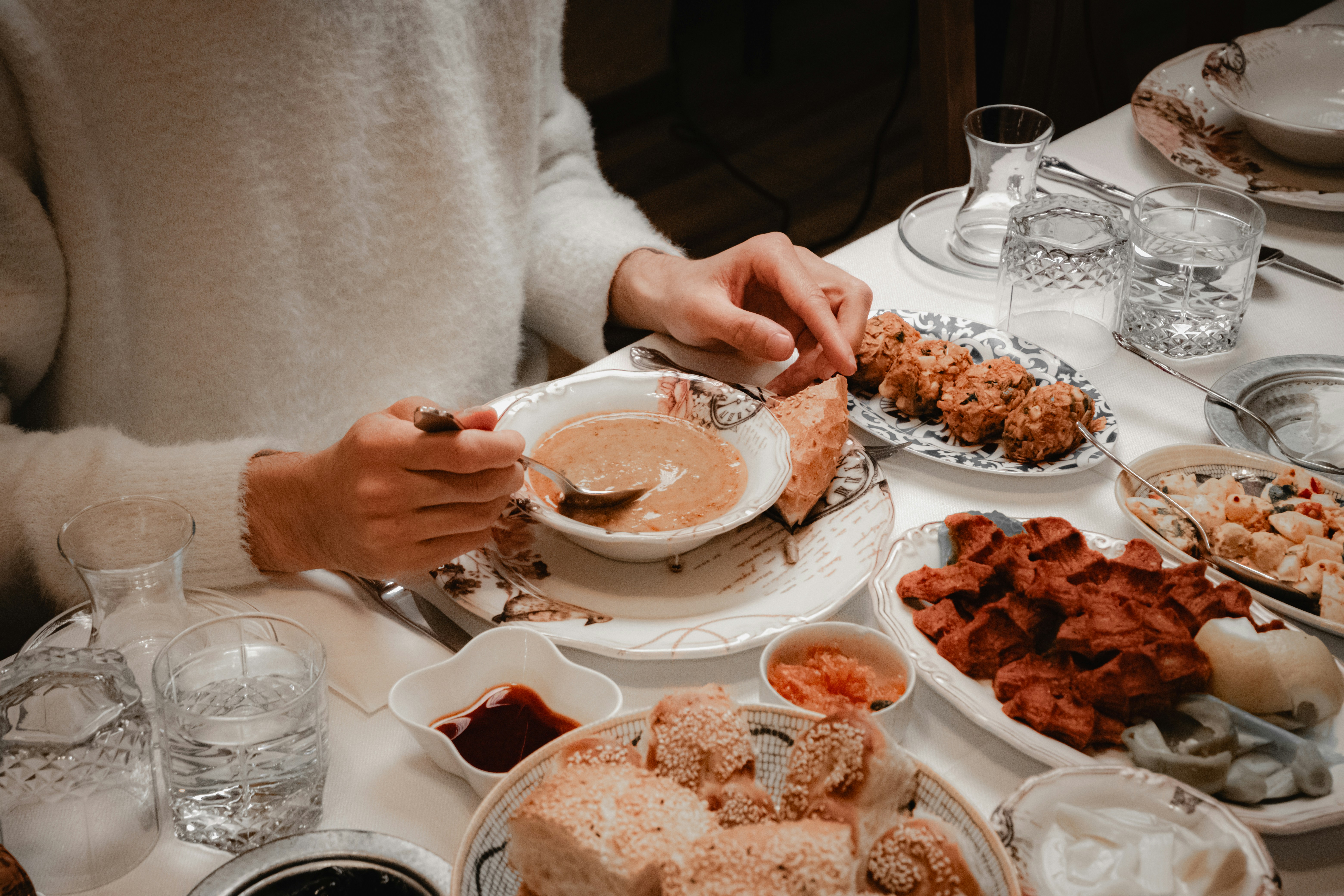 Person eating a bowl of soup with bread and bread