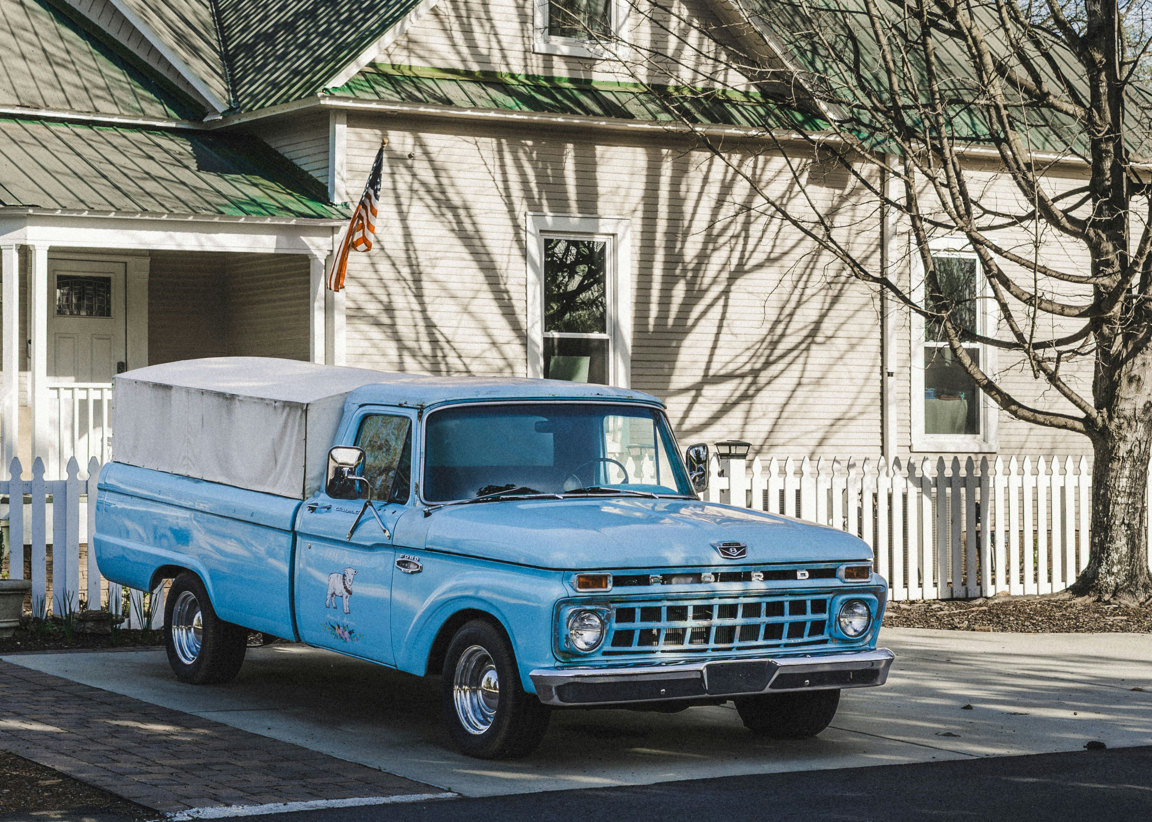 Ein hellblauer Vintage-Pickup, der vor einem Haus geparkt war.