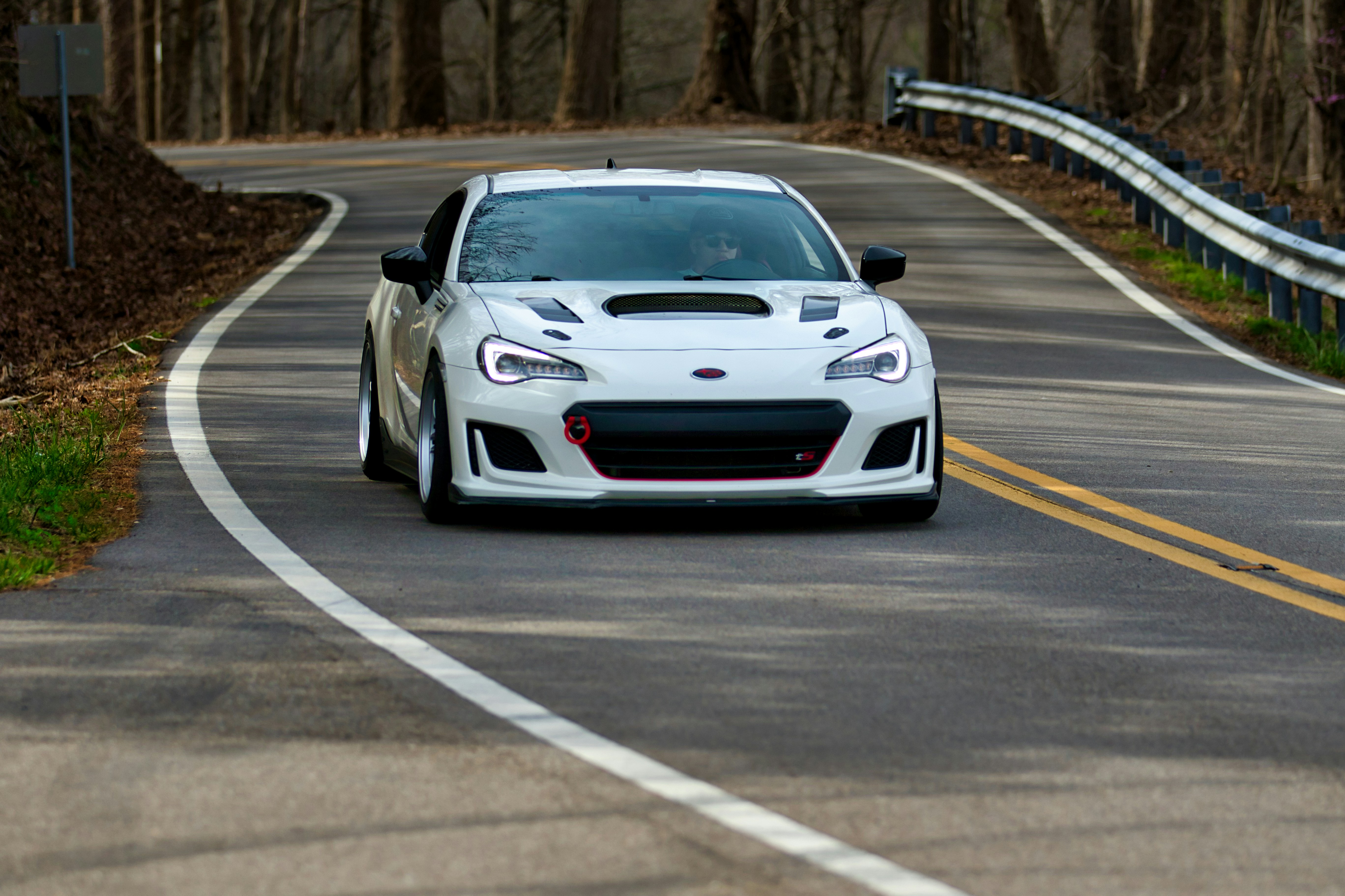 Ein weißer Sportwagen fährt auf einer kurvigen Straße.