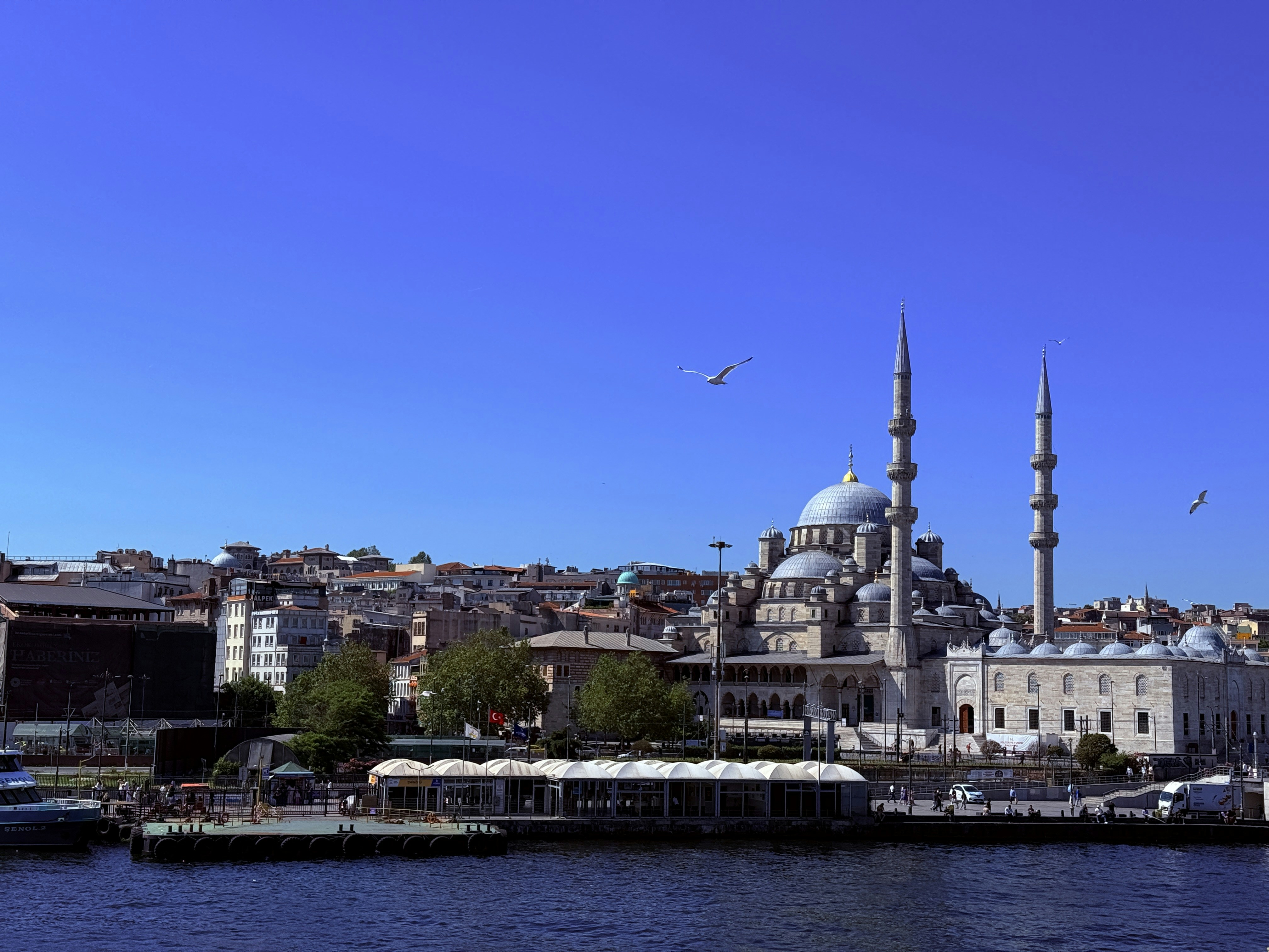 Mosque with minarets by the water under blue sky