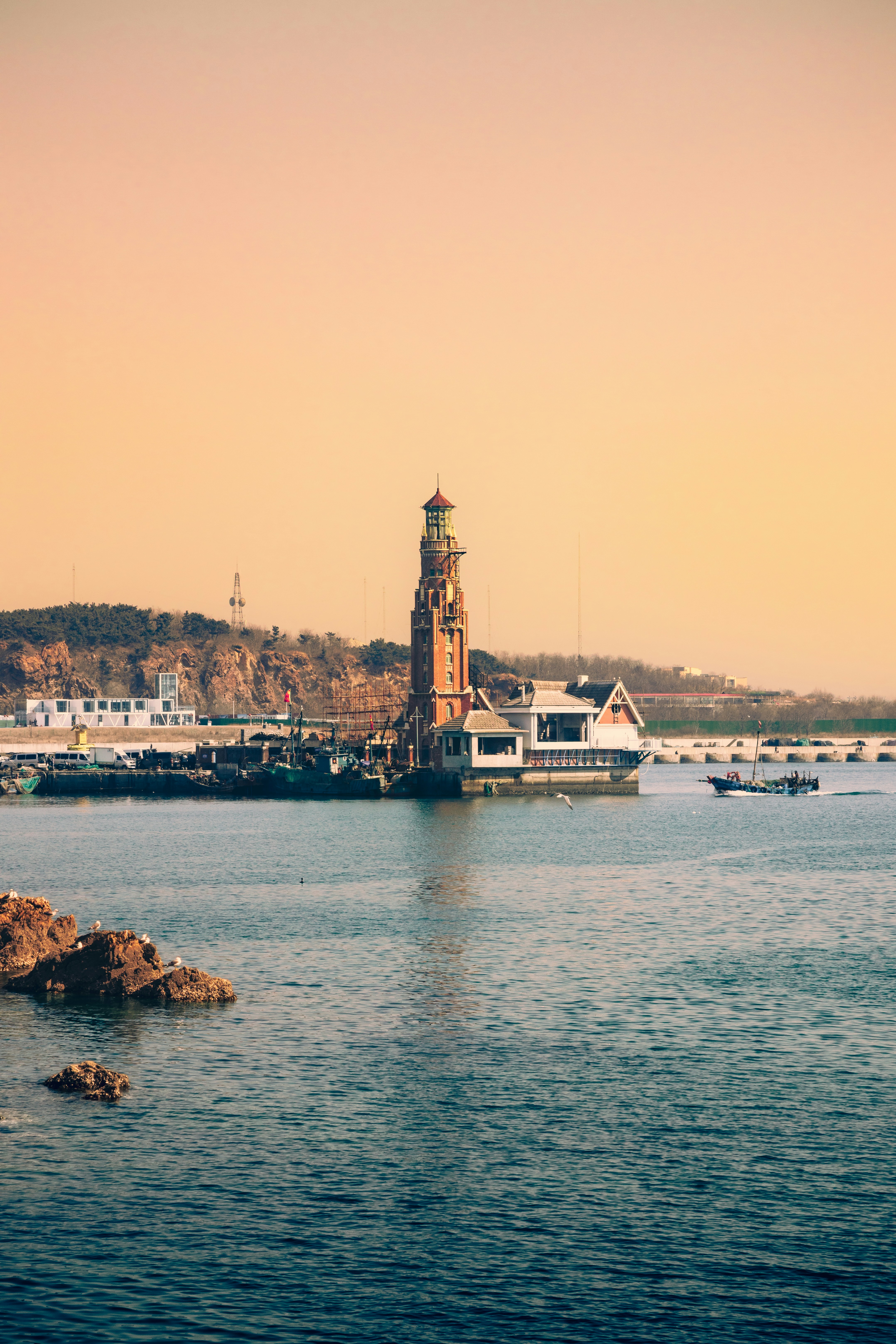 Faro en una costa rocosa con un barco navegando.