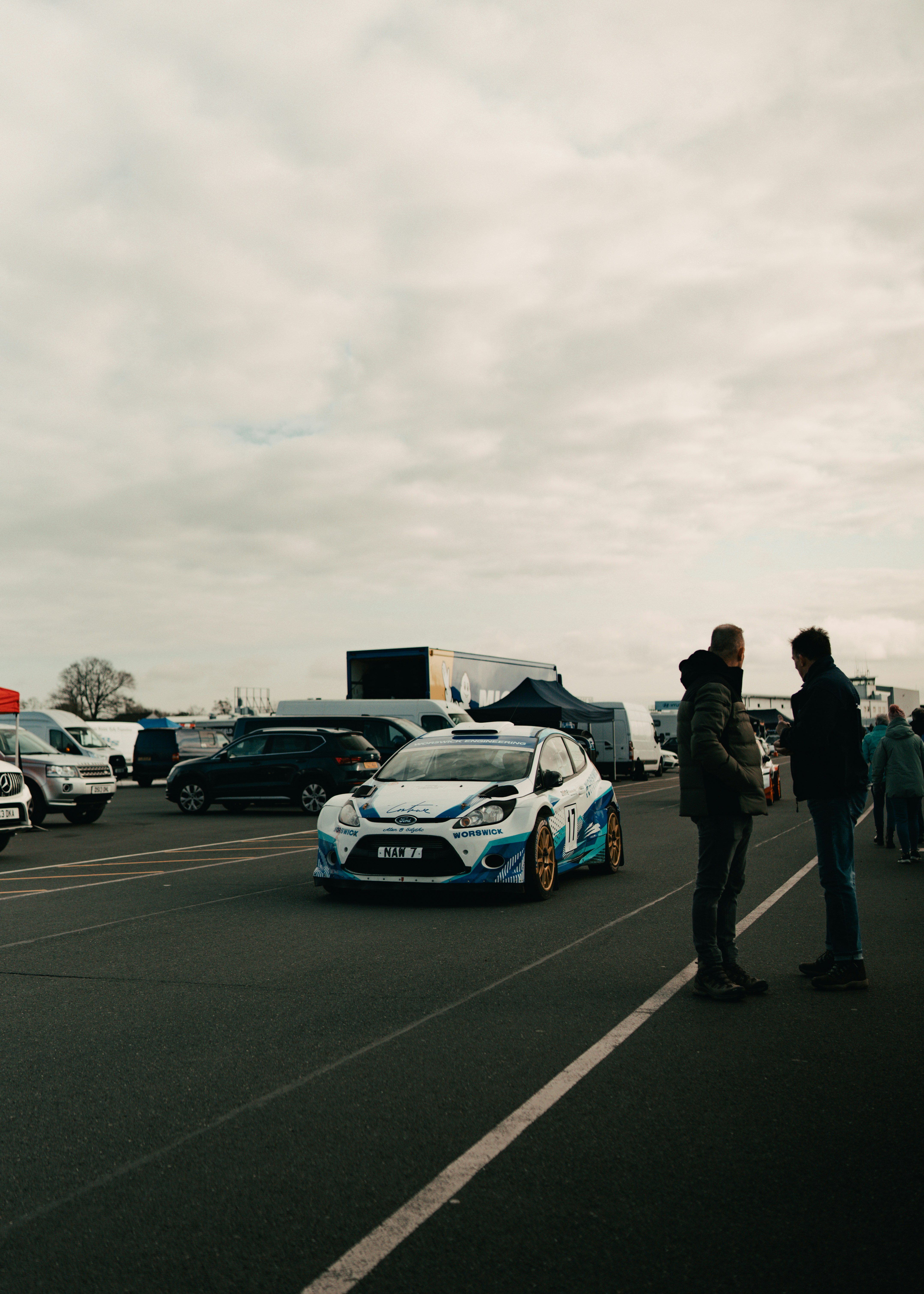 A white rally car on a track with spectators
