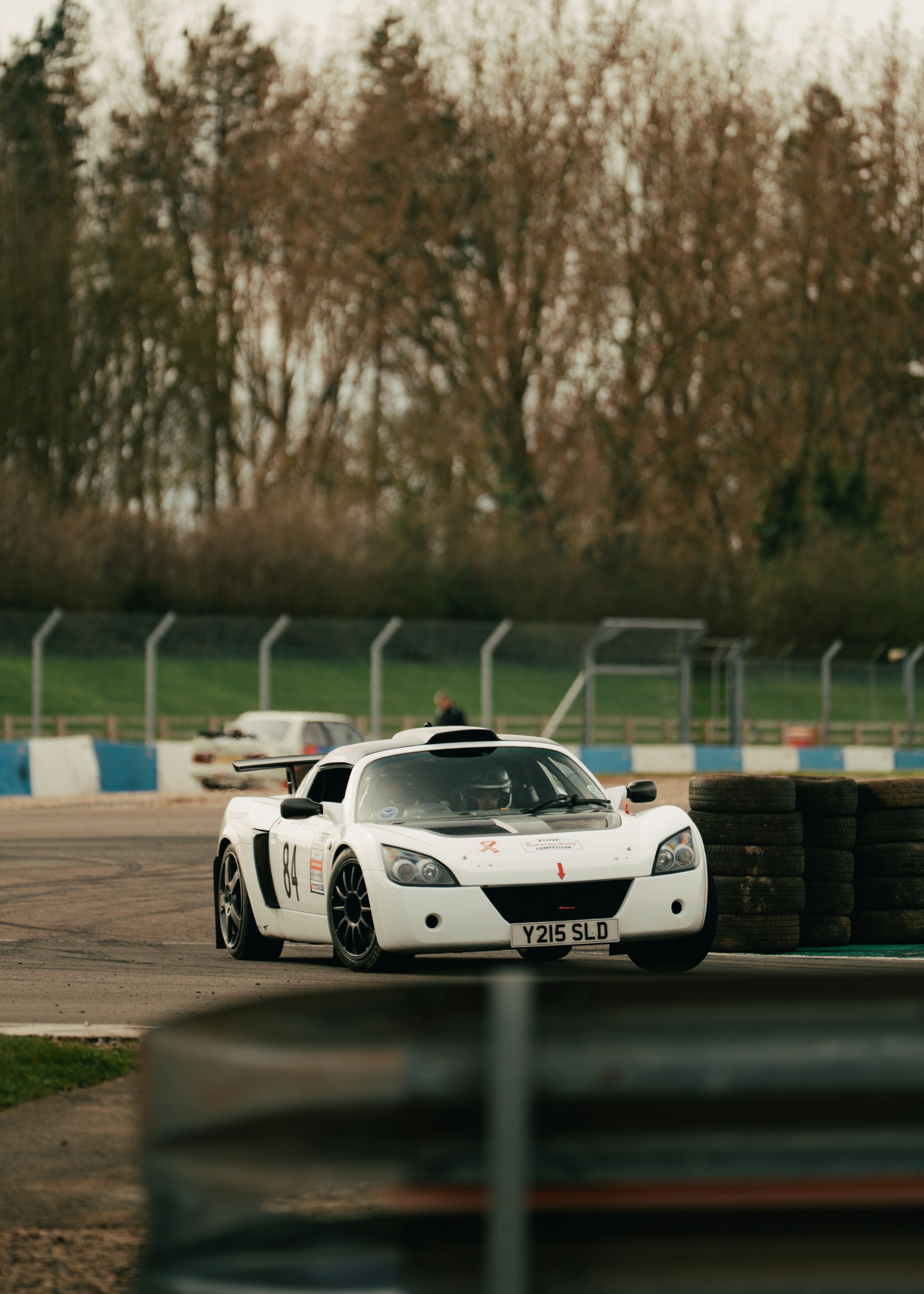A white sports car races on a track.