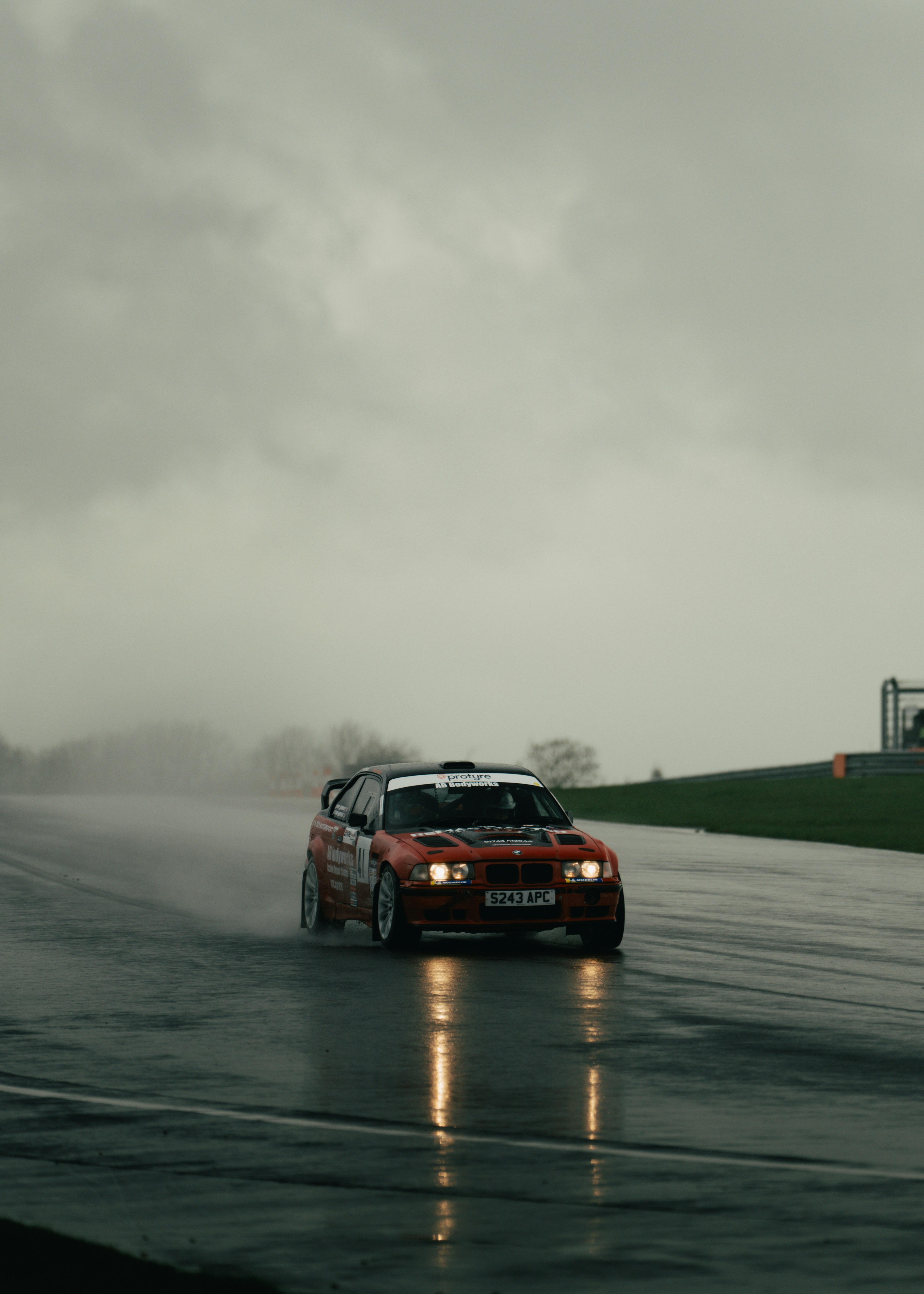 Red race car driving on a wet track.