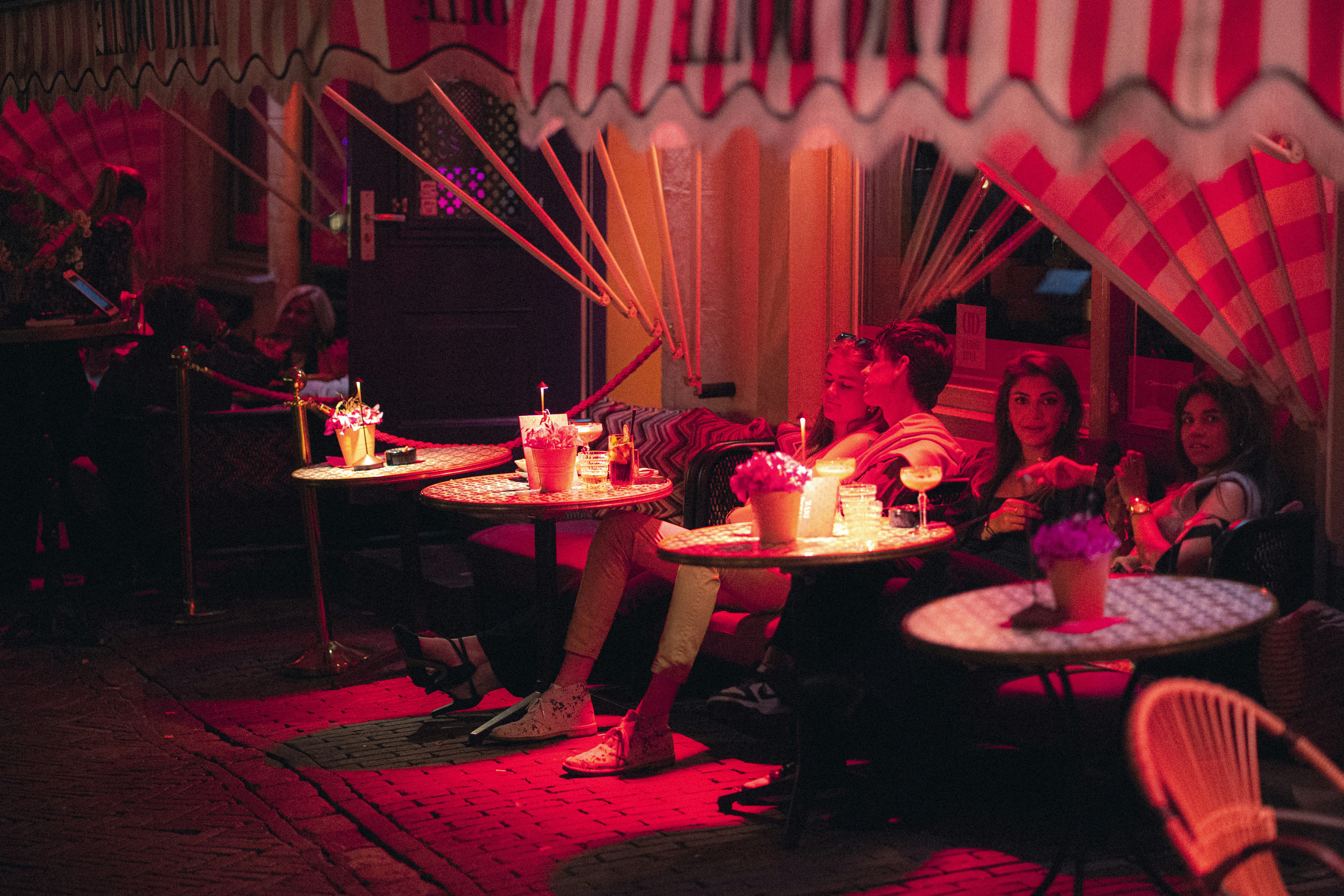 People sitting at tables under red striped awnings