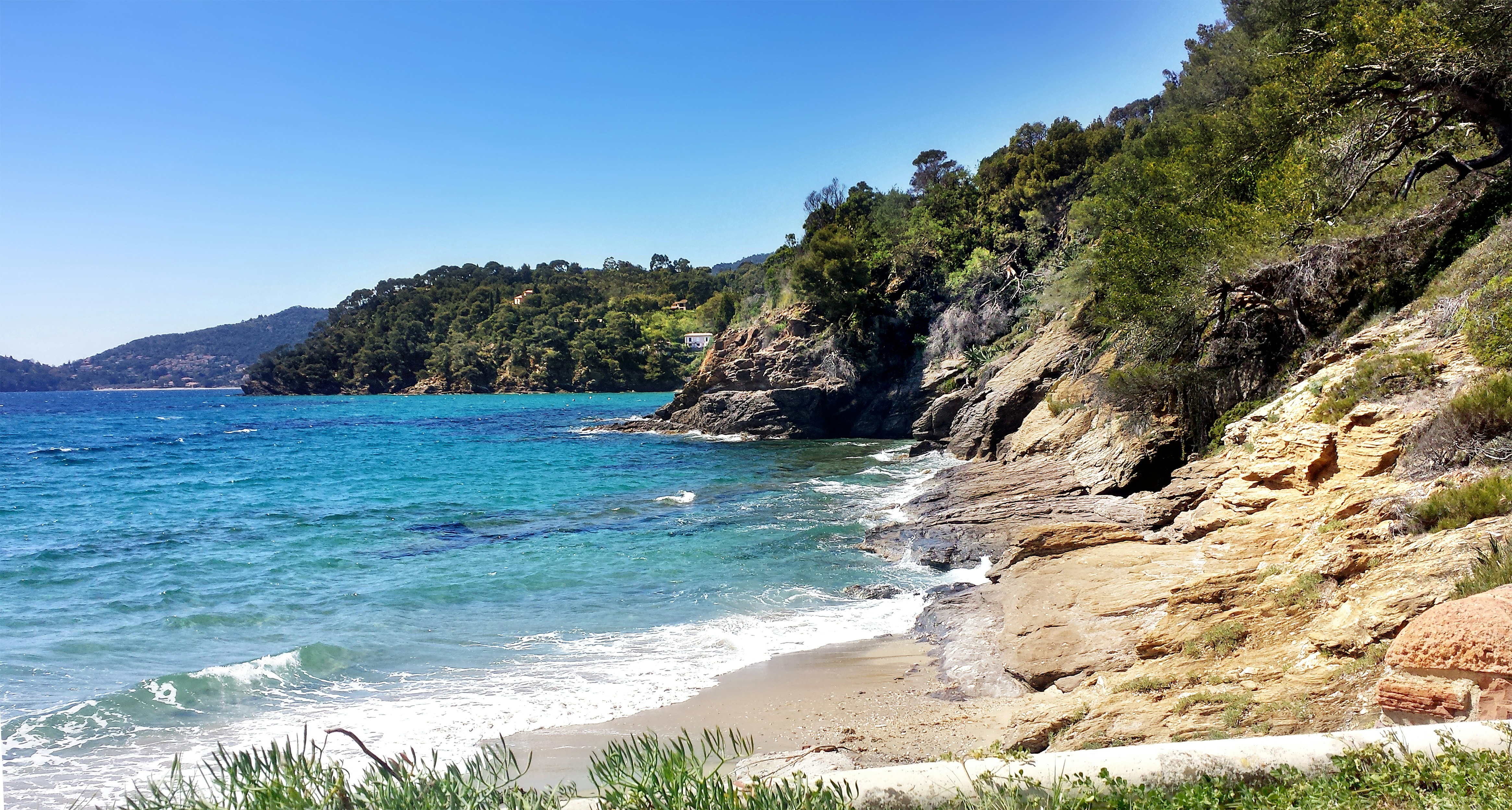 A secluded Mediterranean cove near Domaine du Rayol on the French Riviera. Turquoise water meets a rocky shoreline framed by lush coastal vegetation, creating a peaceful and natural seaside landscape close to Saint-Tropez.