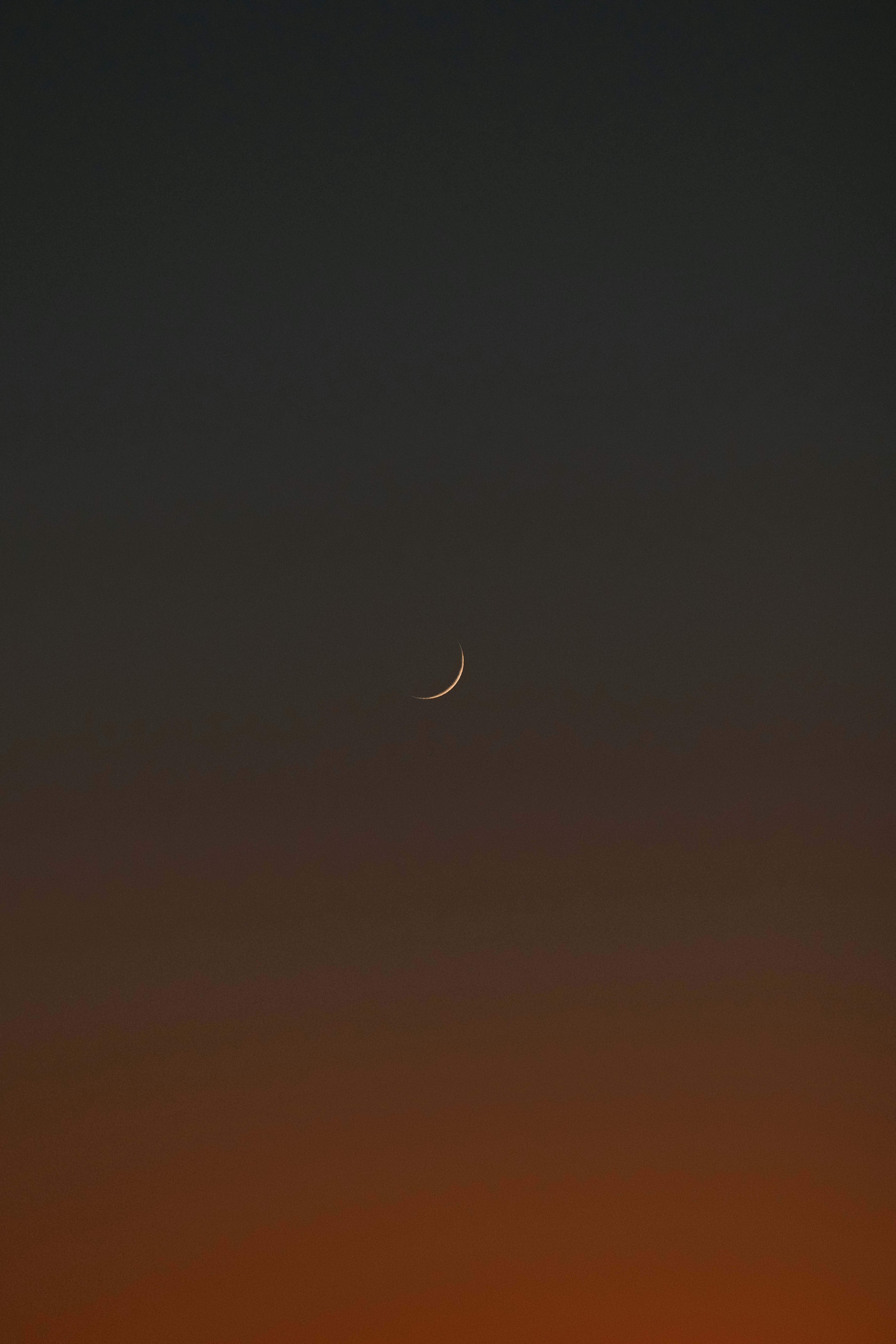 Una luna creciente en un cielo oscuro y degradado