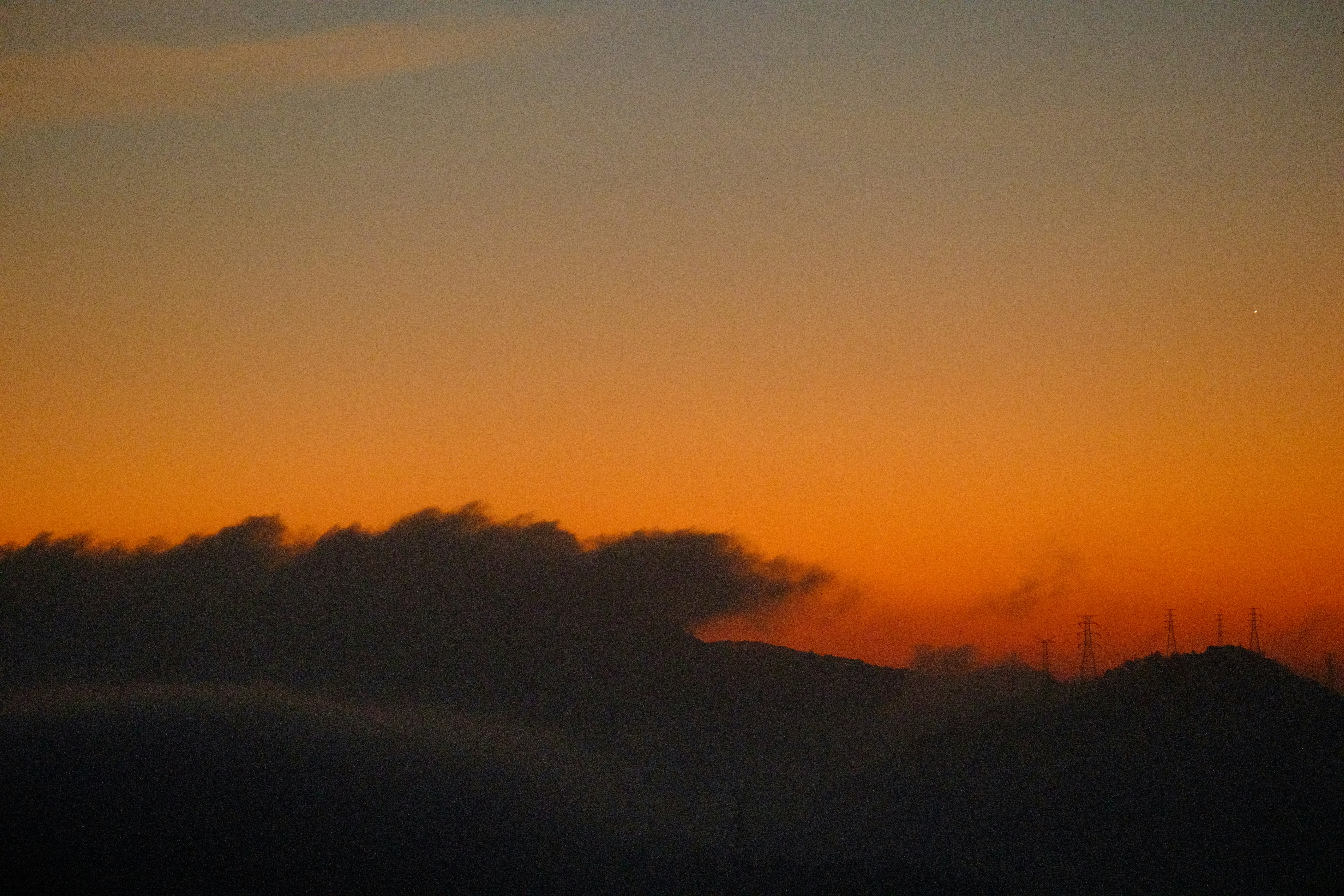 Cielo naranja sobre montañas oscuras y nubes