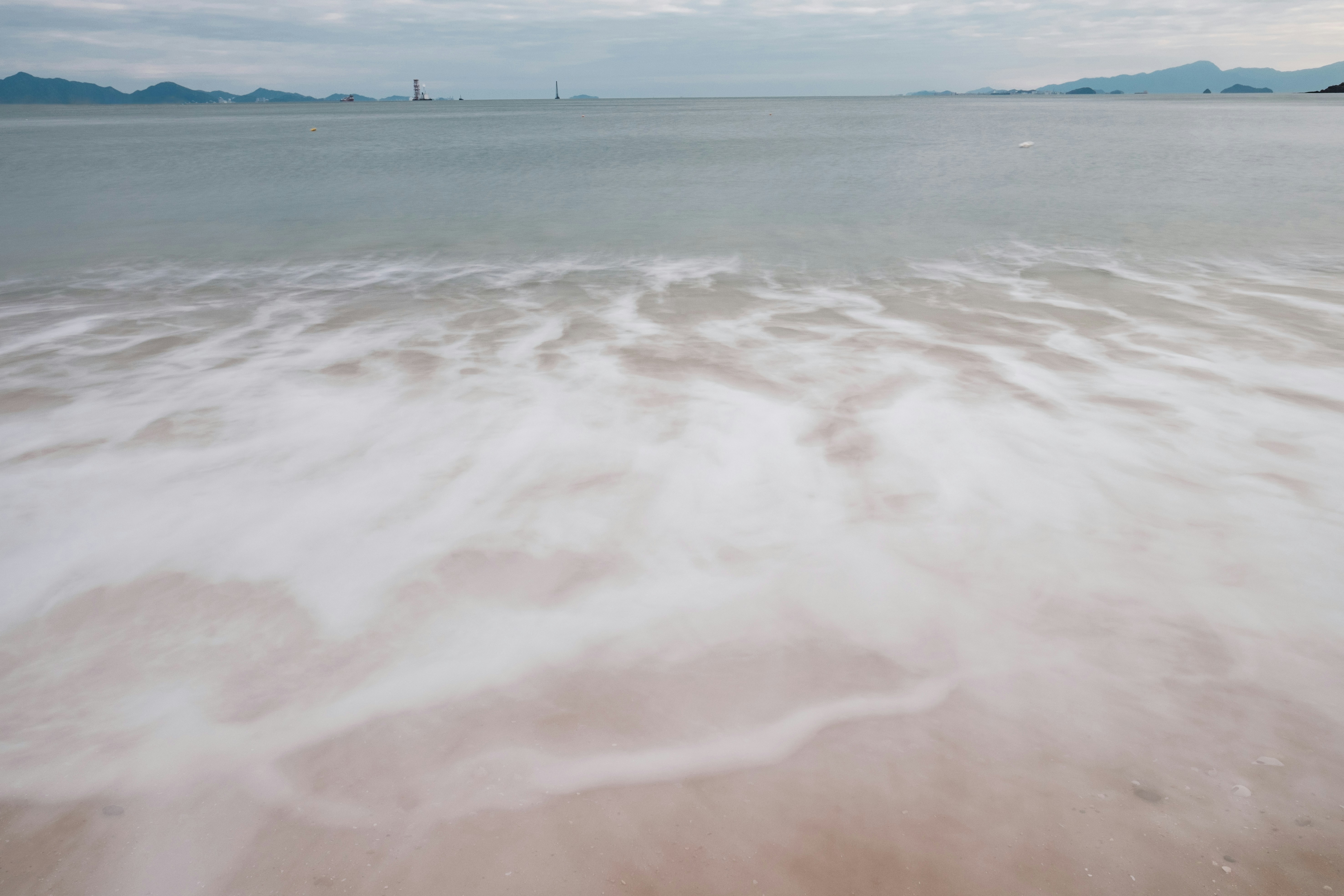 Olas suaves bañan una playa de arena al anochecer.