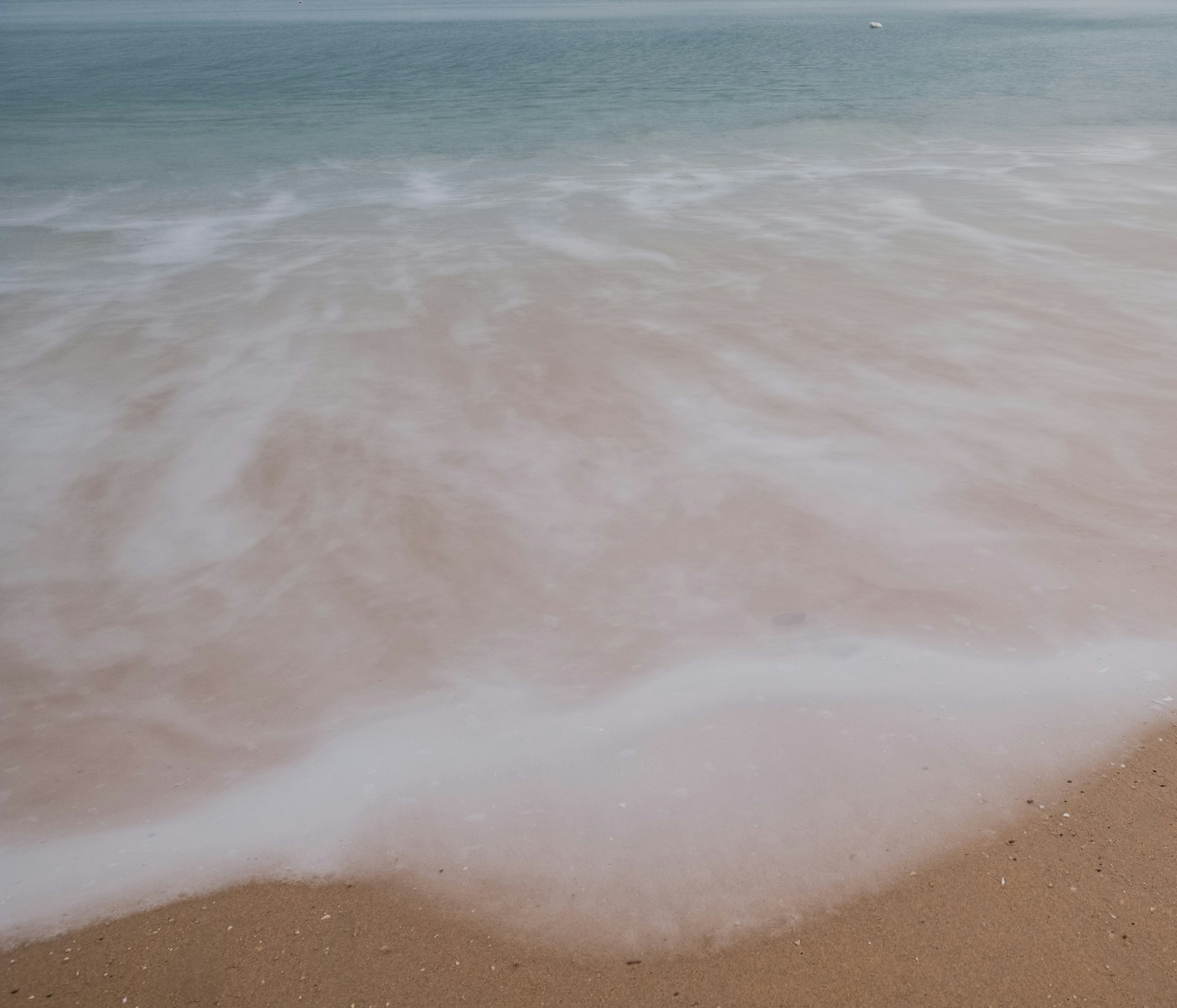 Olas suaves llegan a una orilla arenosa.