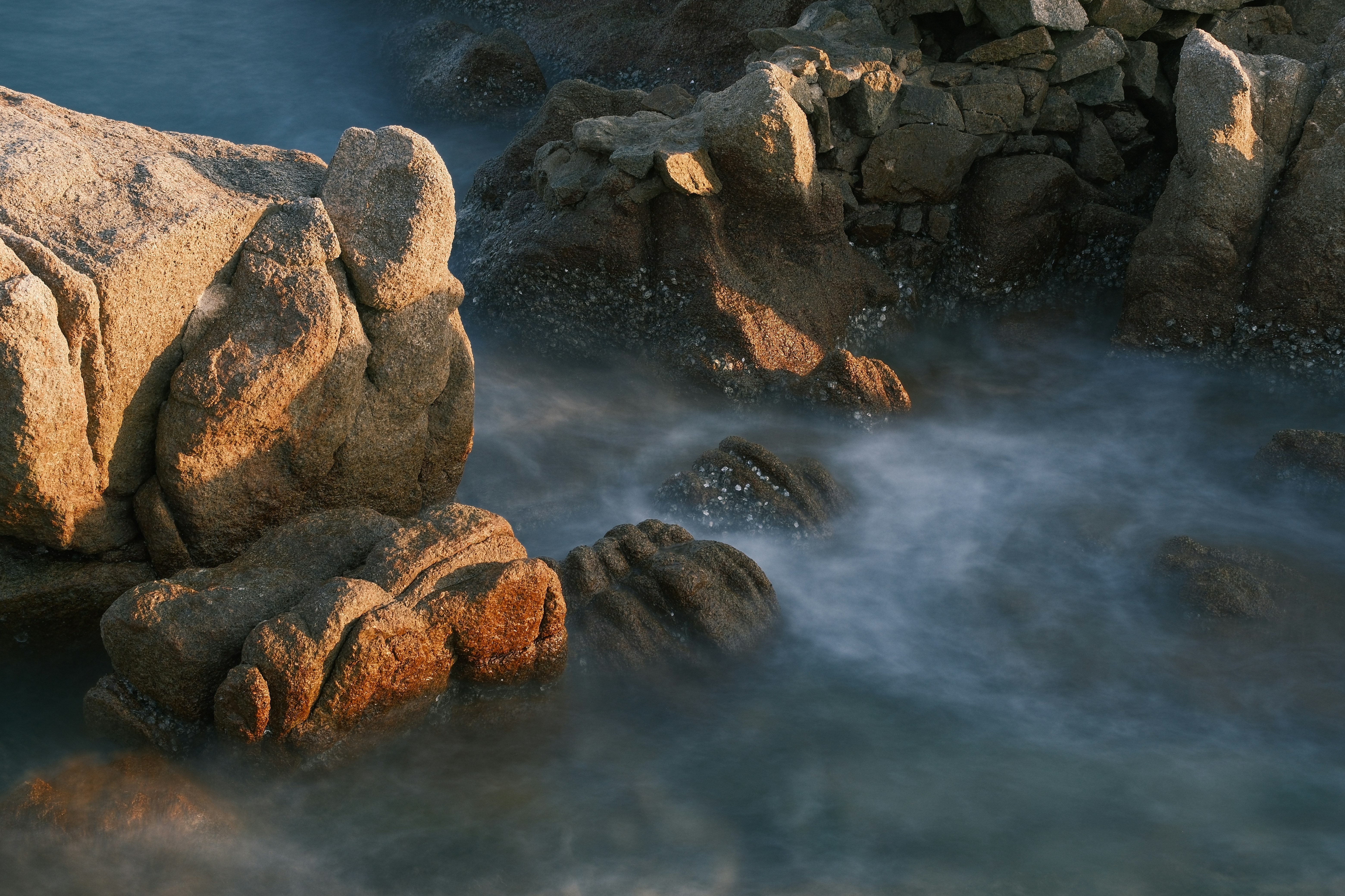El agua tranquila del océano fluye alrededor de grandes rocas.