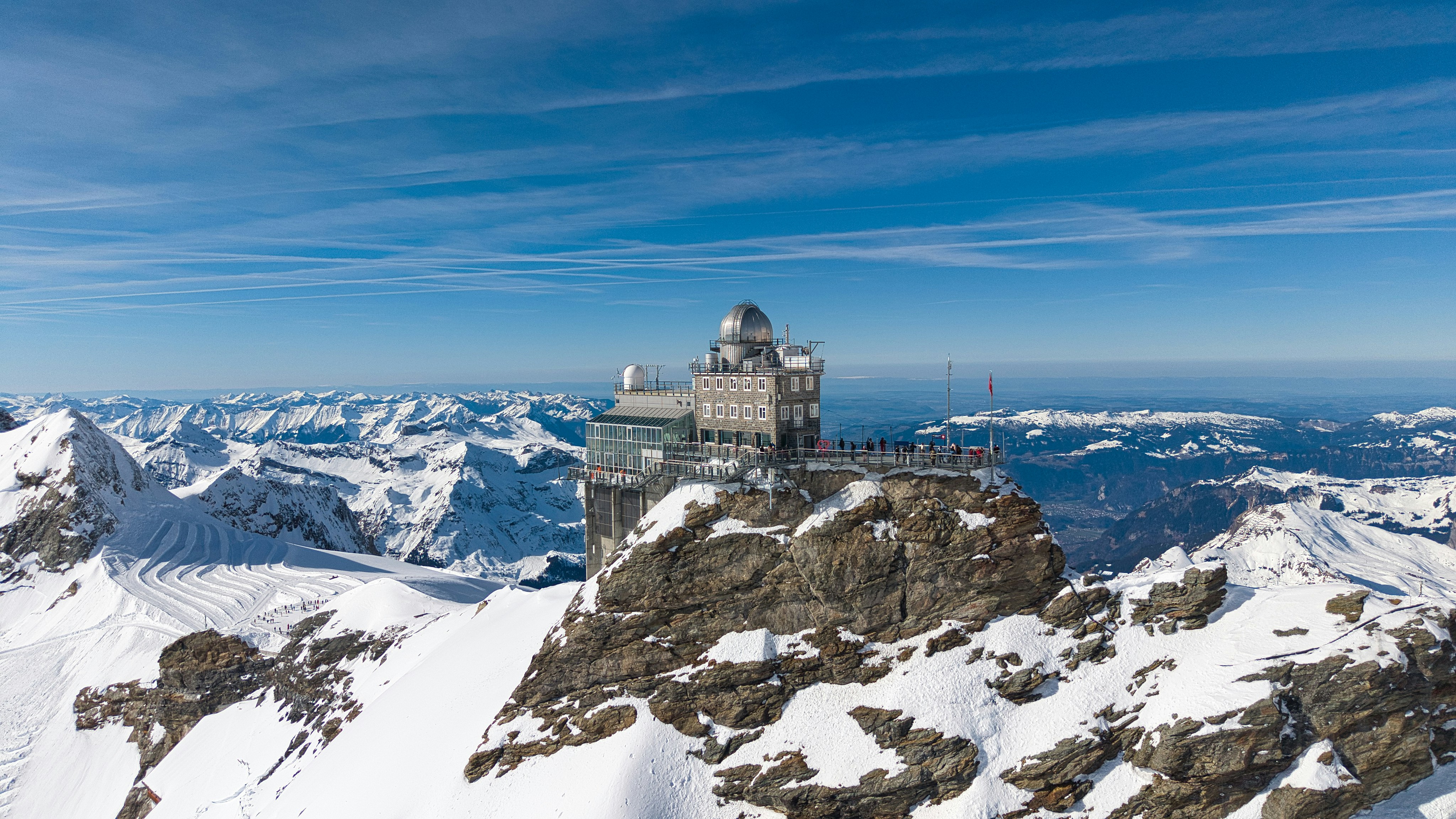 Modern building perched on a snowy mountain peak.