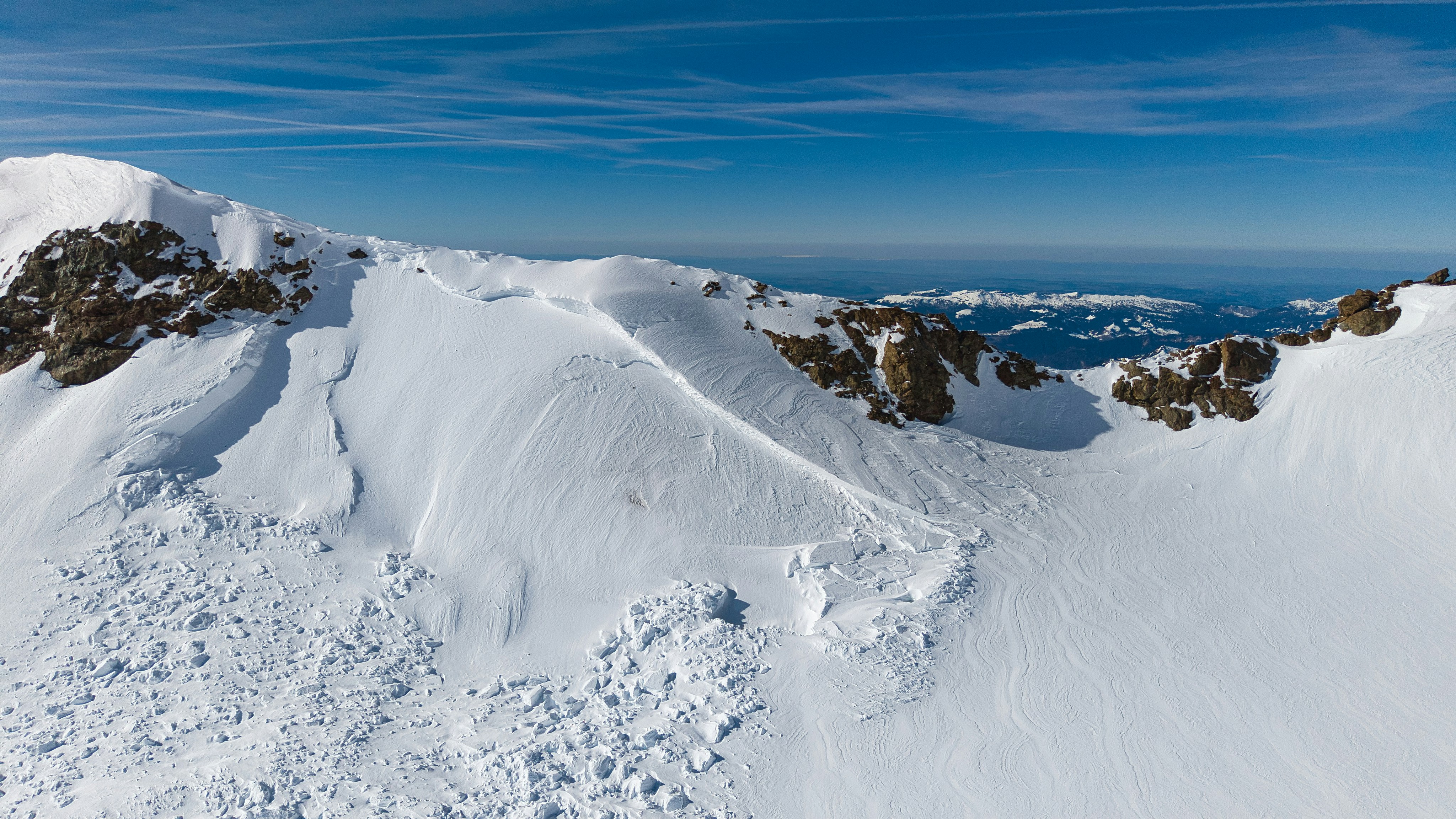 Snowy mountain landscape with rocky outcrops under blue sky