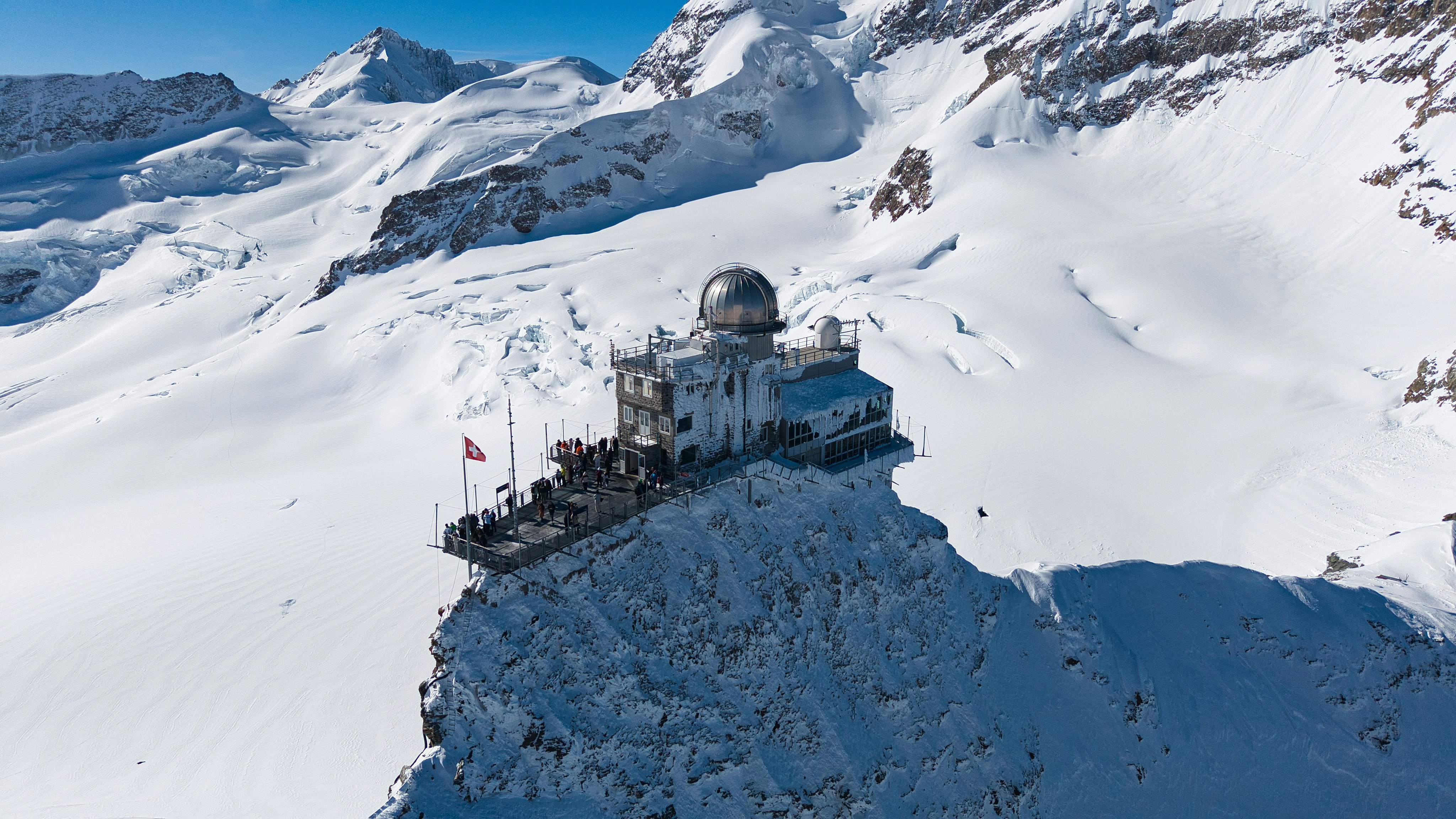 A building sits atop a snow-covered mountain peak.