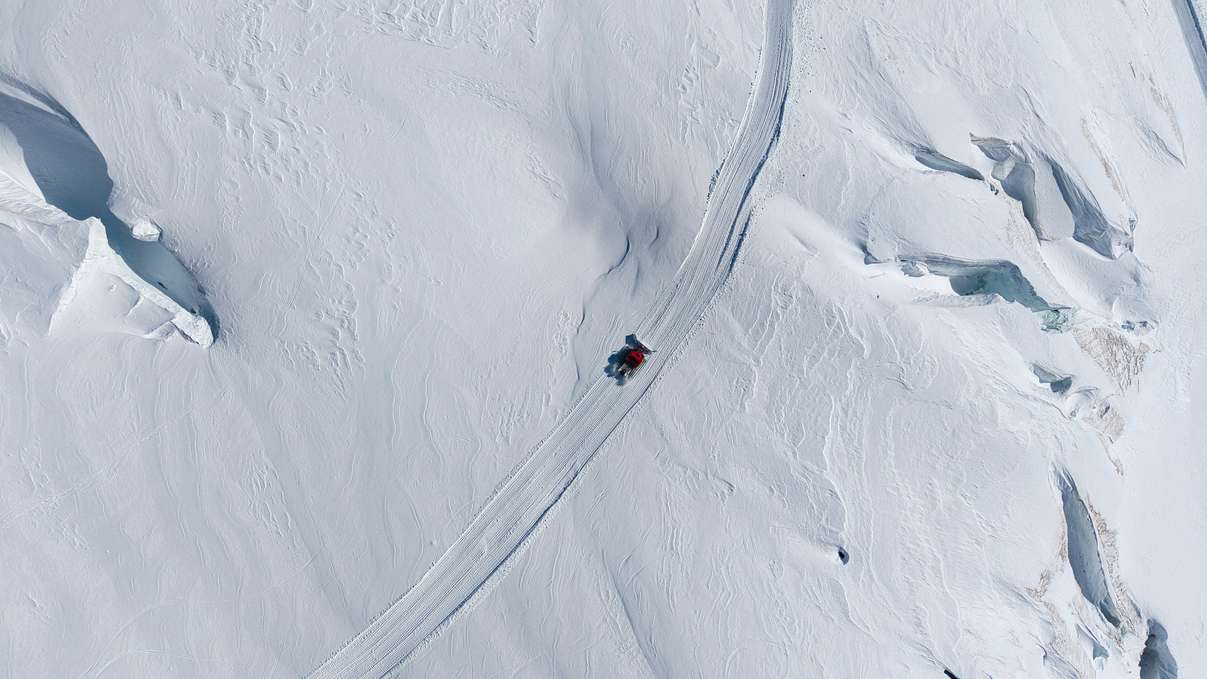 A snowmobile travels on a snowy mountain path.