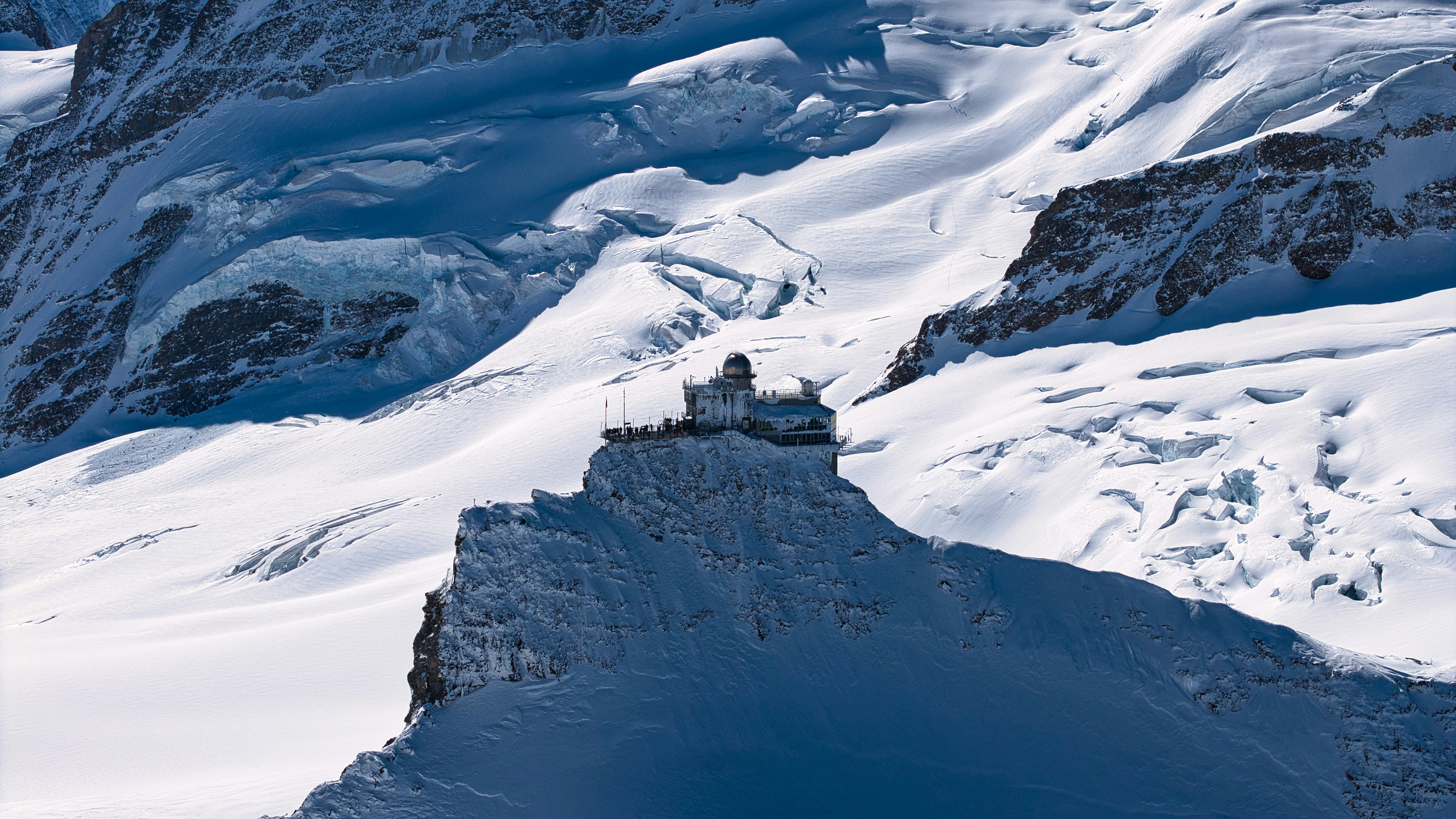 Snowy mountain range with a building on a cliff