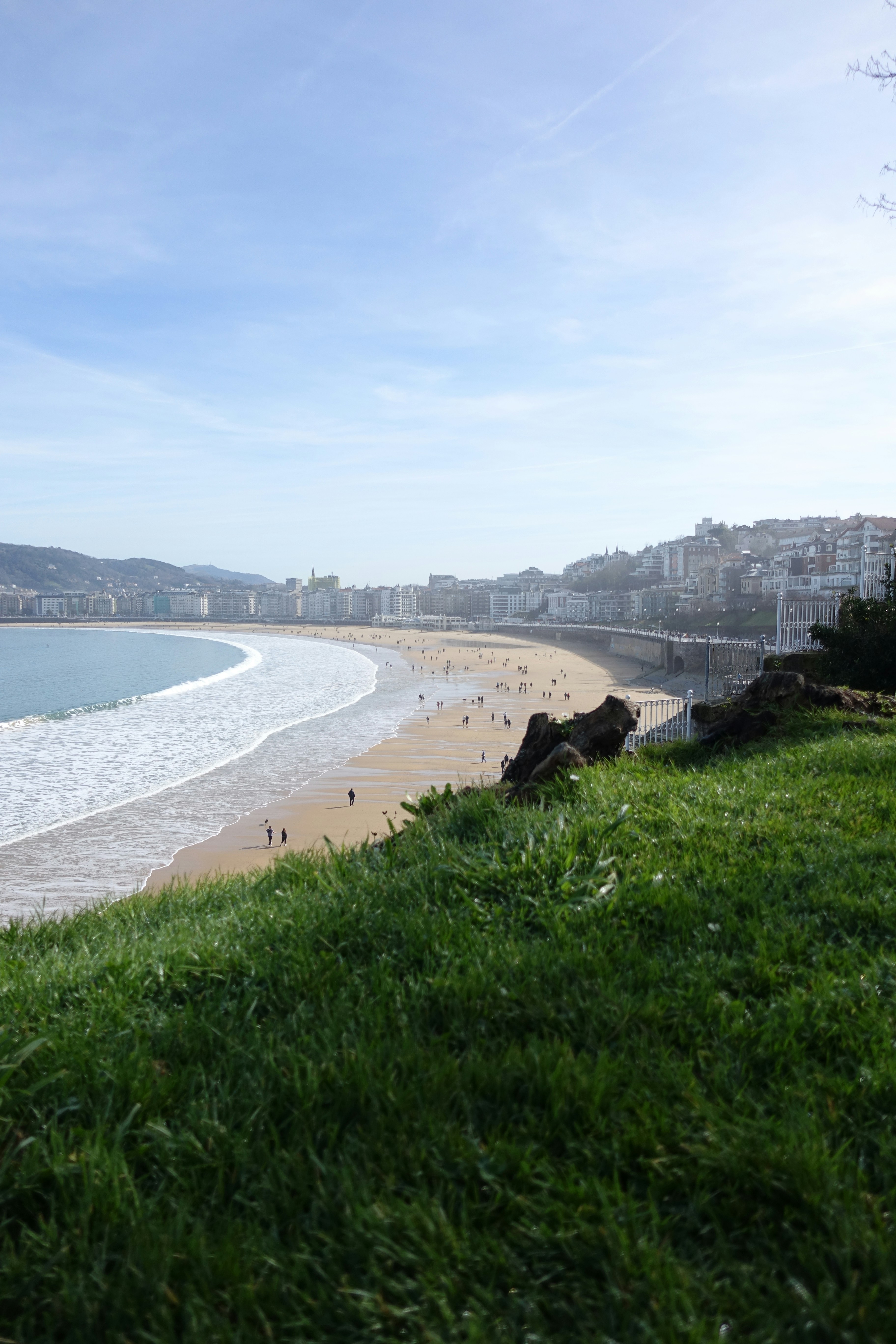 Beach with gentle waves and distant city skyline.