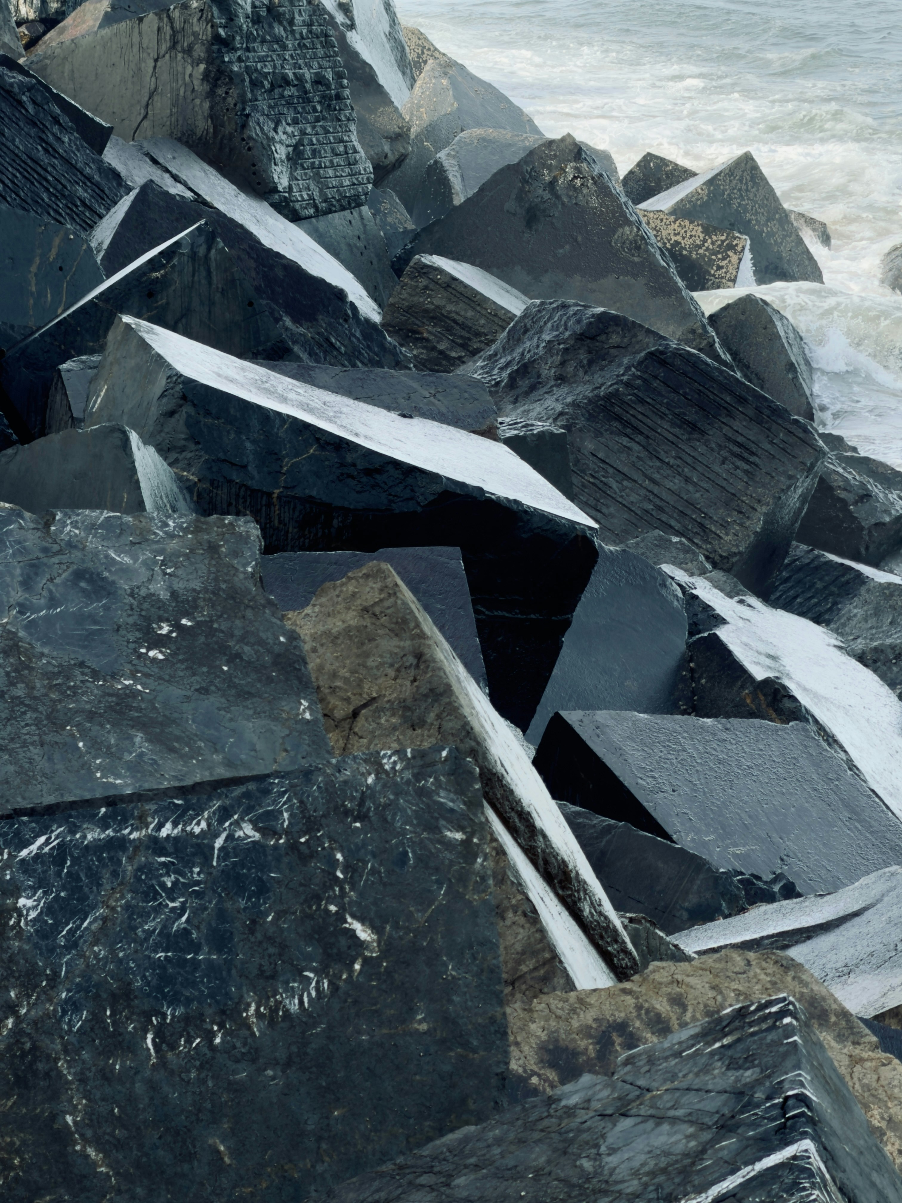 Jagged, dark rocks form a breakwater against the ocean.
