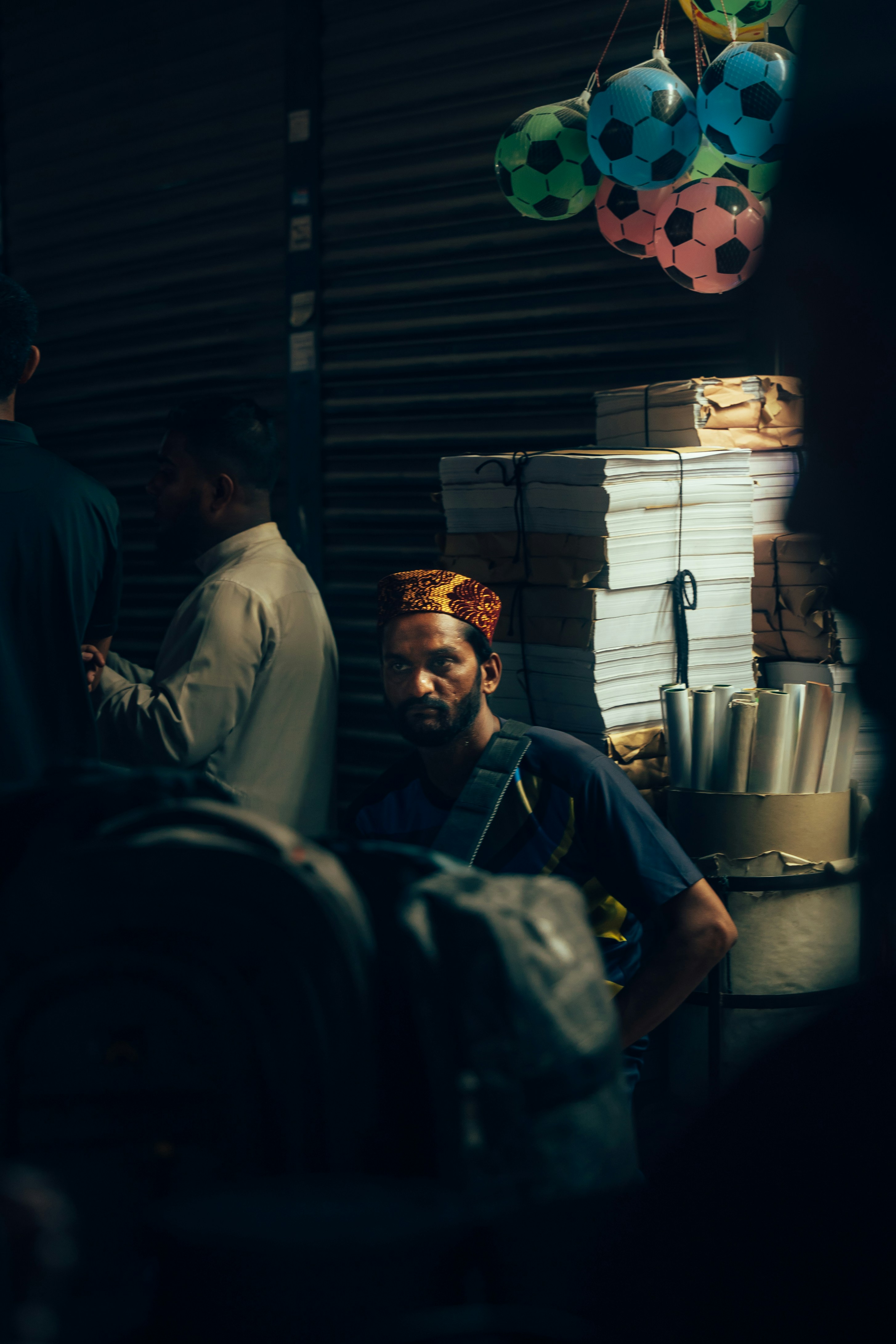 Homme avec des ballons de foot colorés sur un stand de marché.