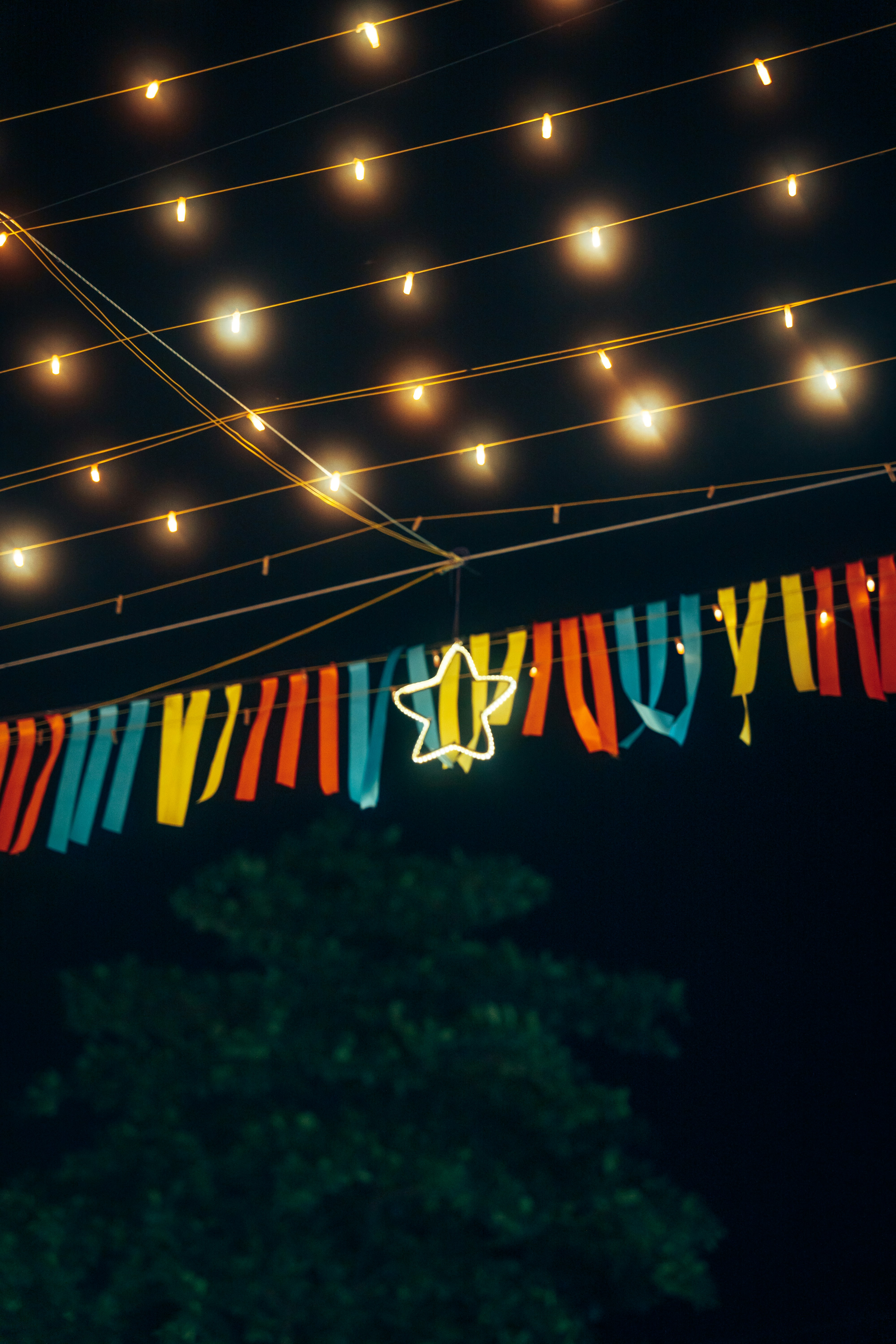 Des guirlandes lumineuses et des serpentins colorés sont suspendus la nuit.