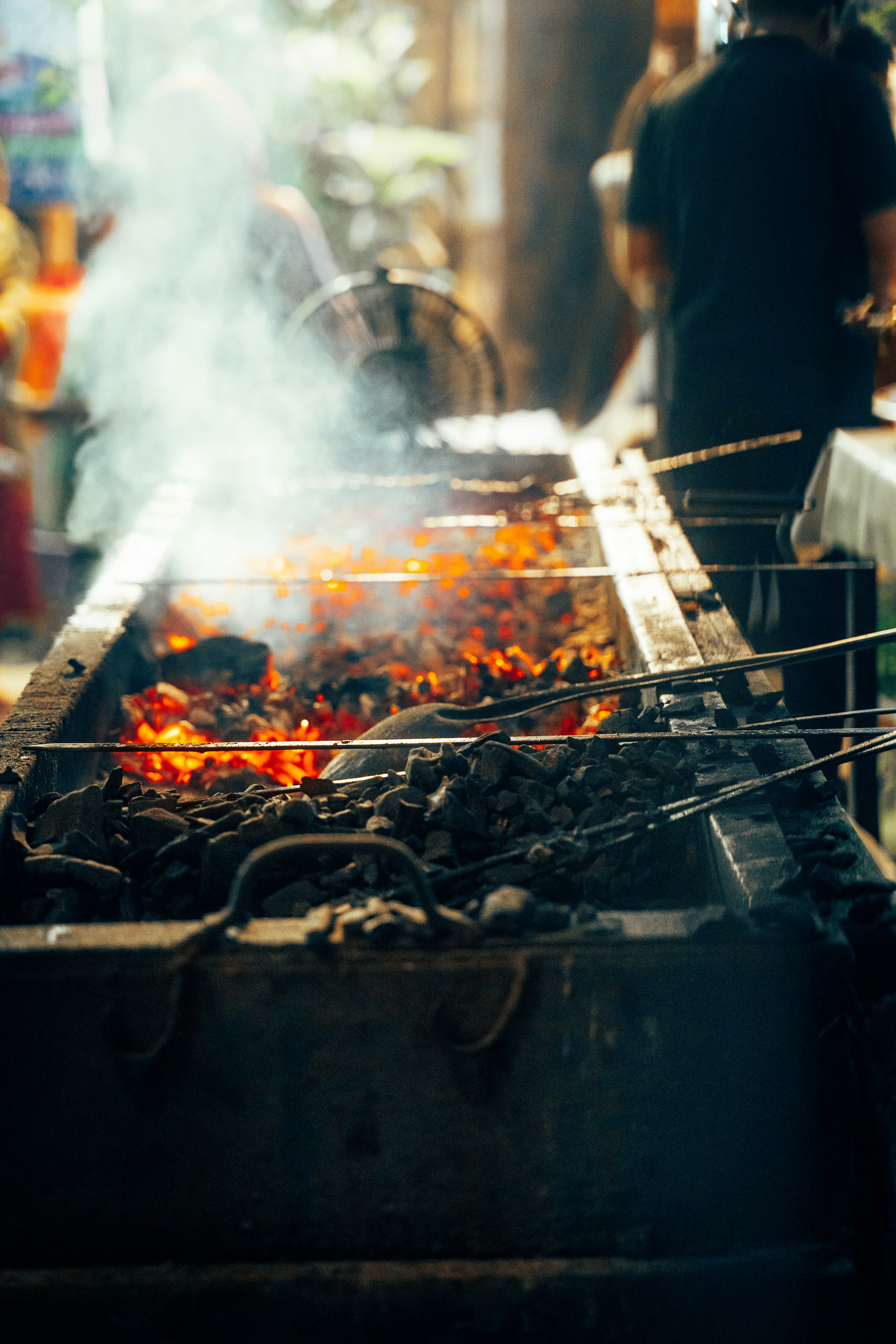 Des braises brûlantes s’élevant dans une forge, de la fumée s’élevant.