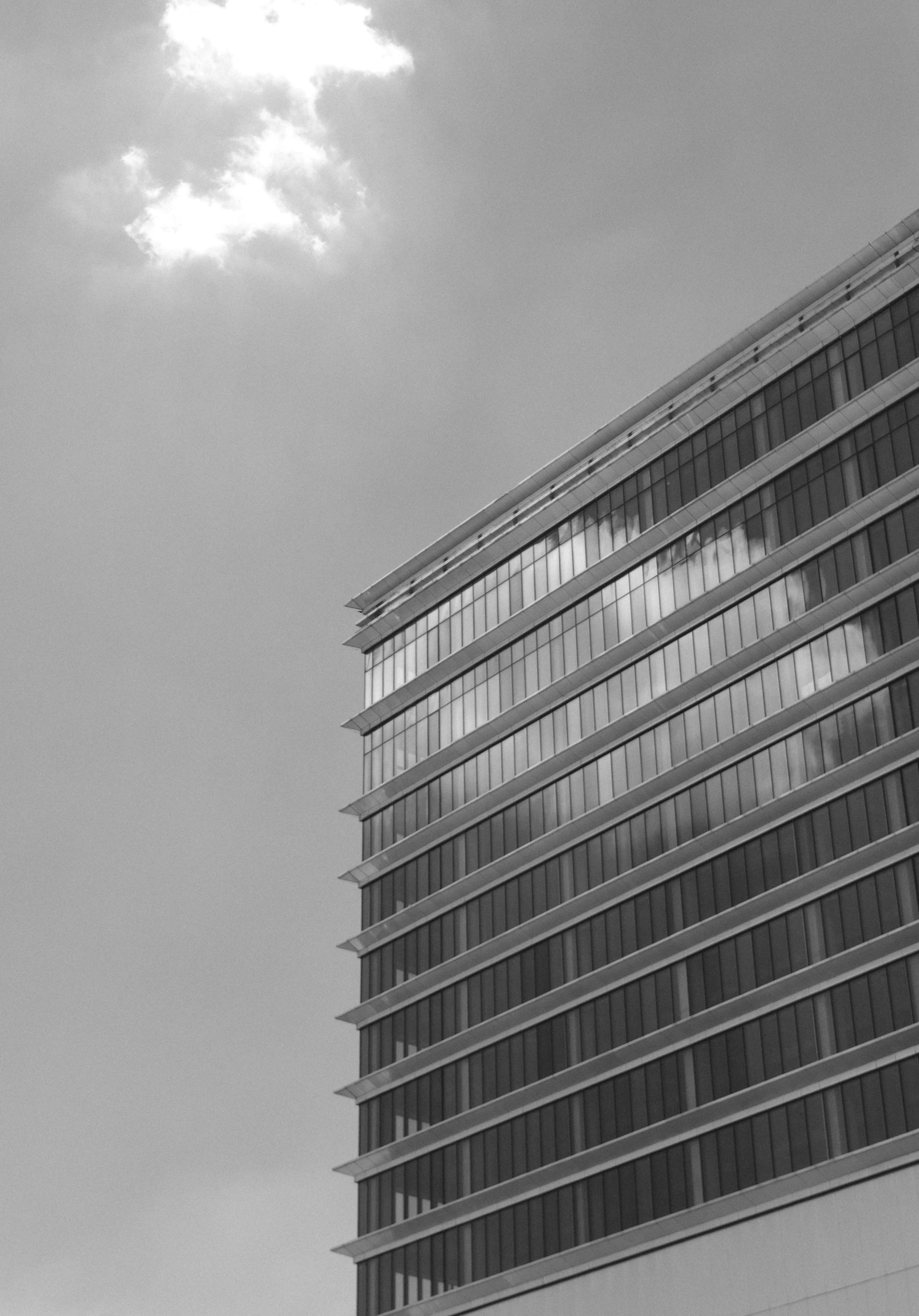 Modern glass building facade reflecting the sky and clouds.