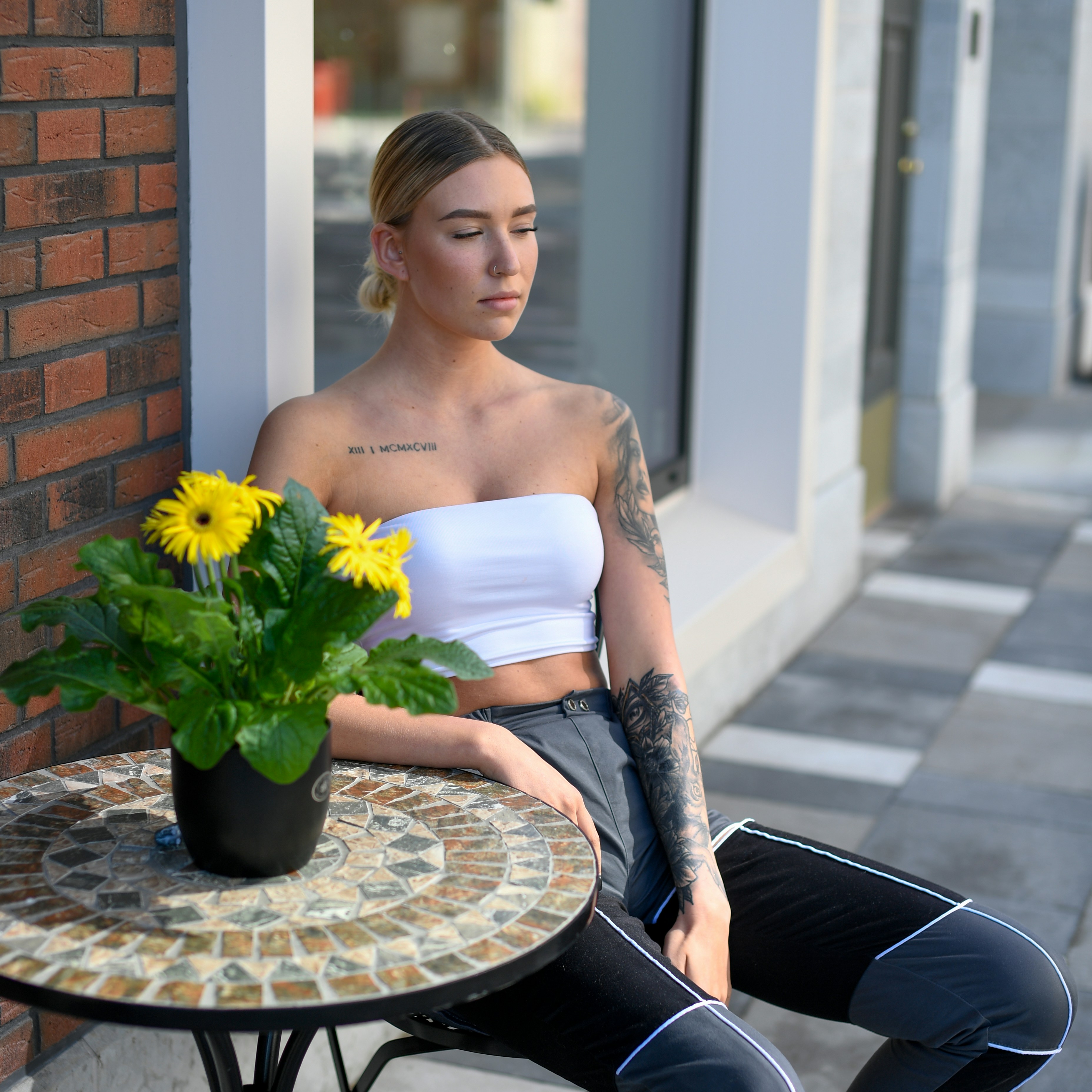 Woman sitting at a table with a potted plant.
