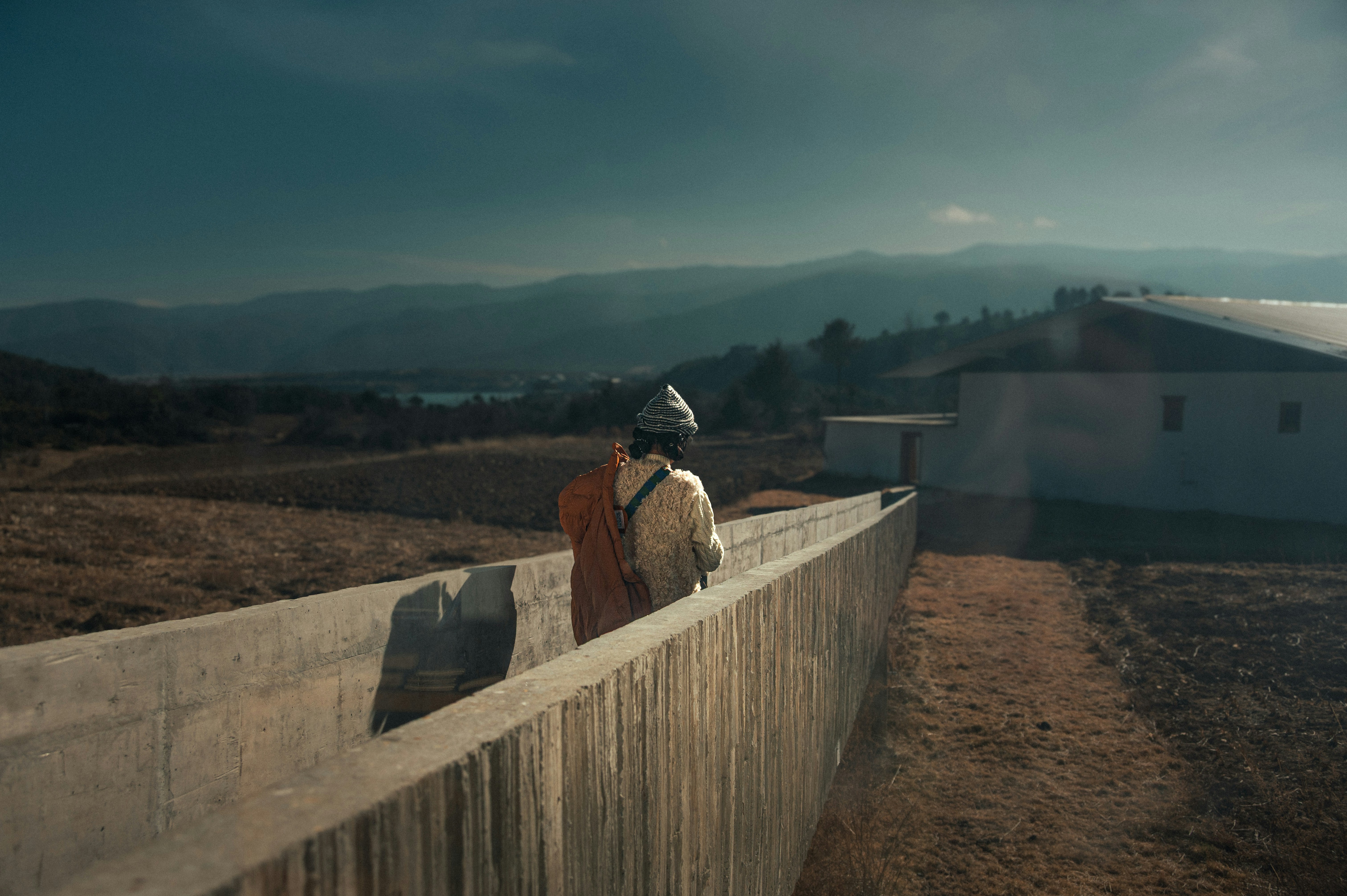 ローブを着た人物がコンクリートの構造物の上を歩いている