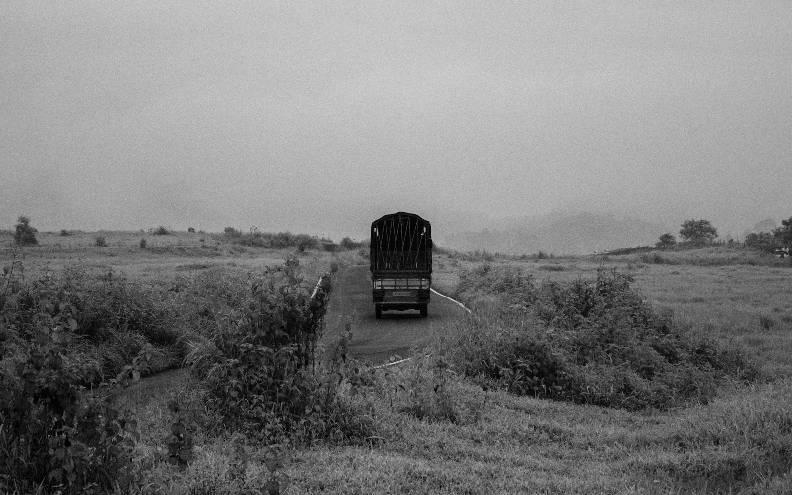 Truck driving down a rural road through fields