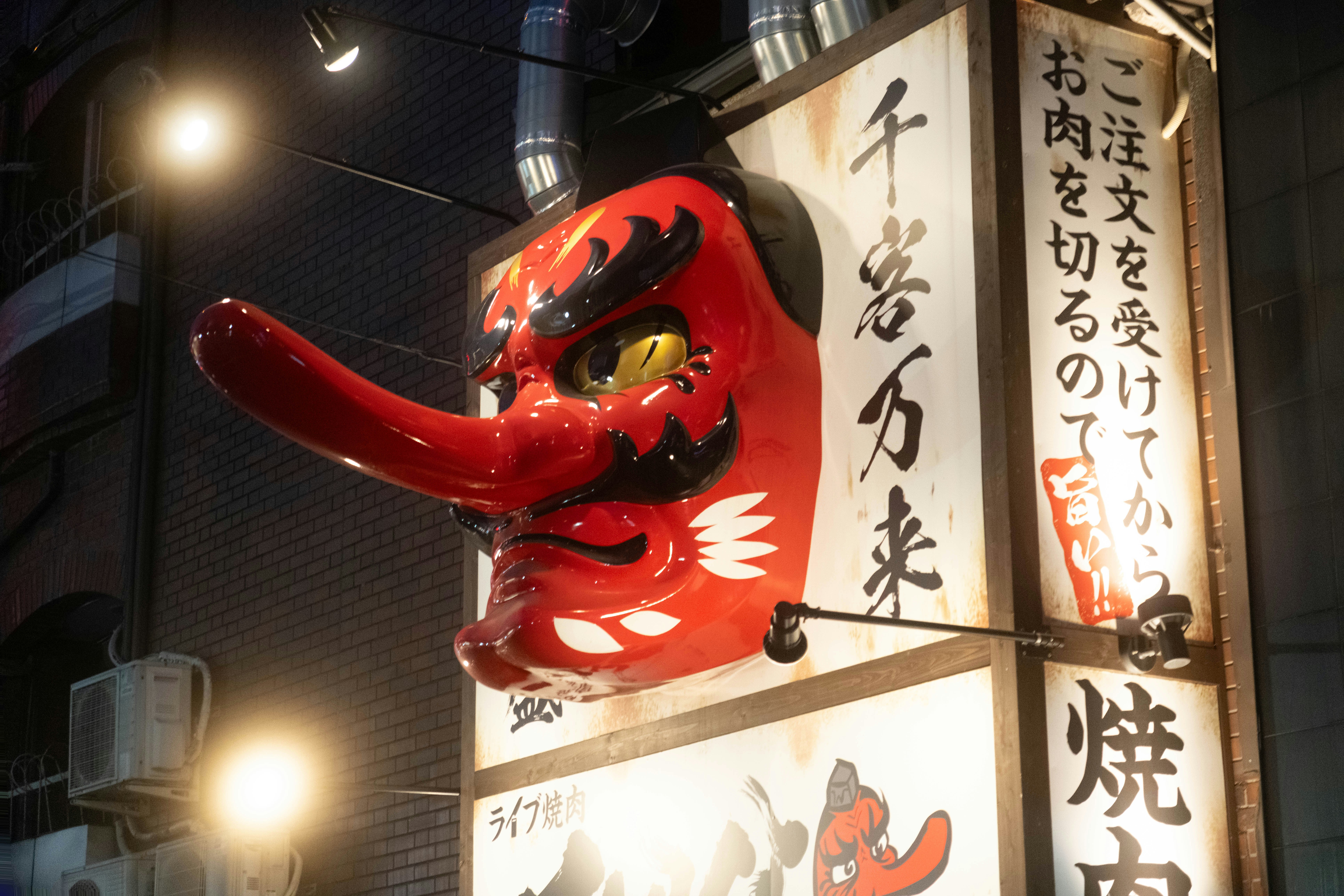 A large red tengu mask decoration on a sign