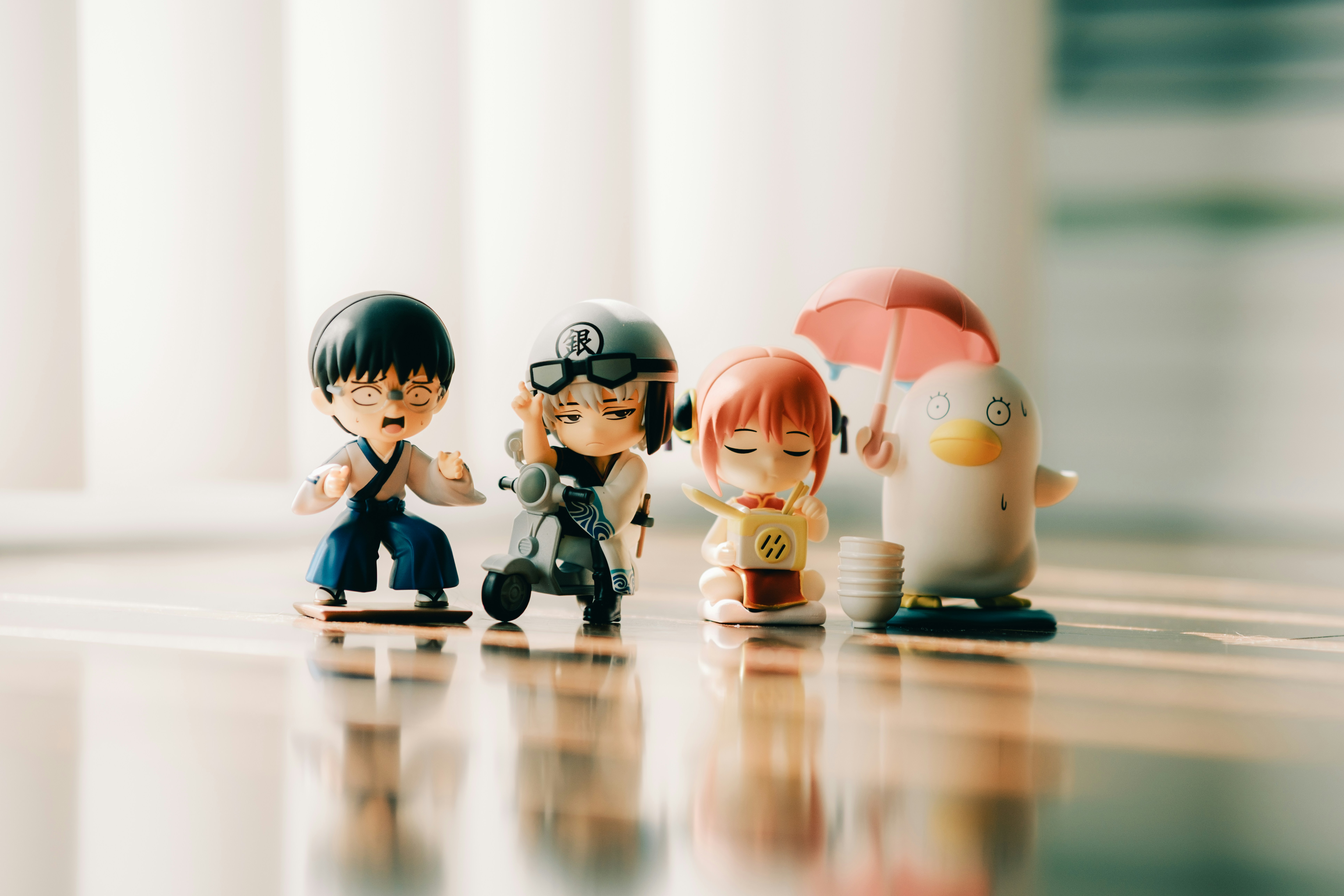 Four small figurines stand together on a reflective surface.