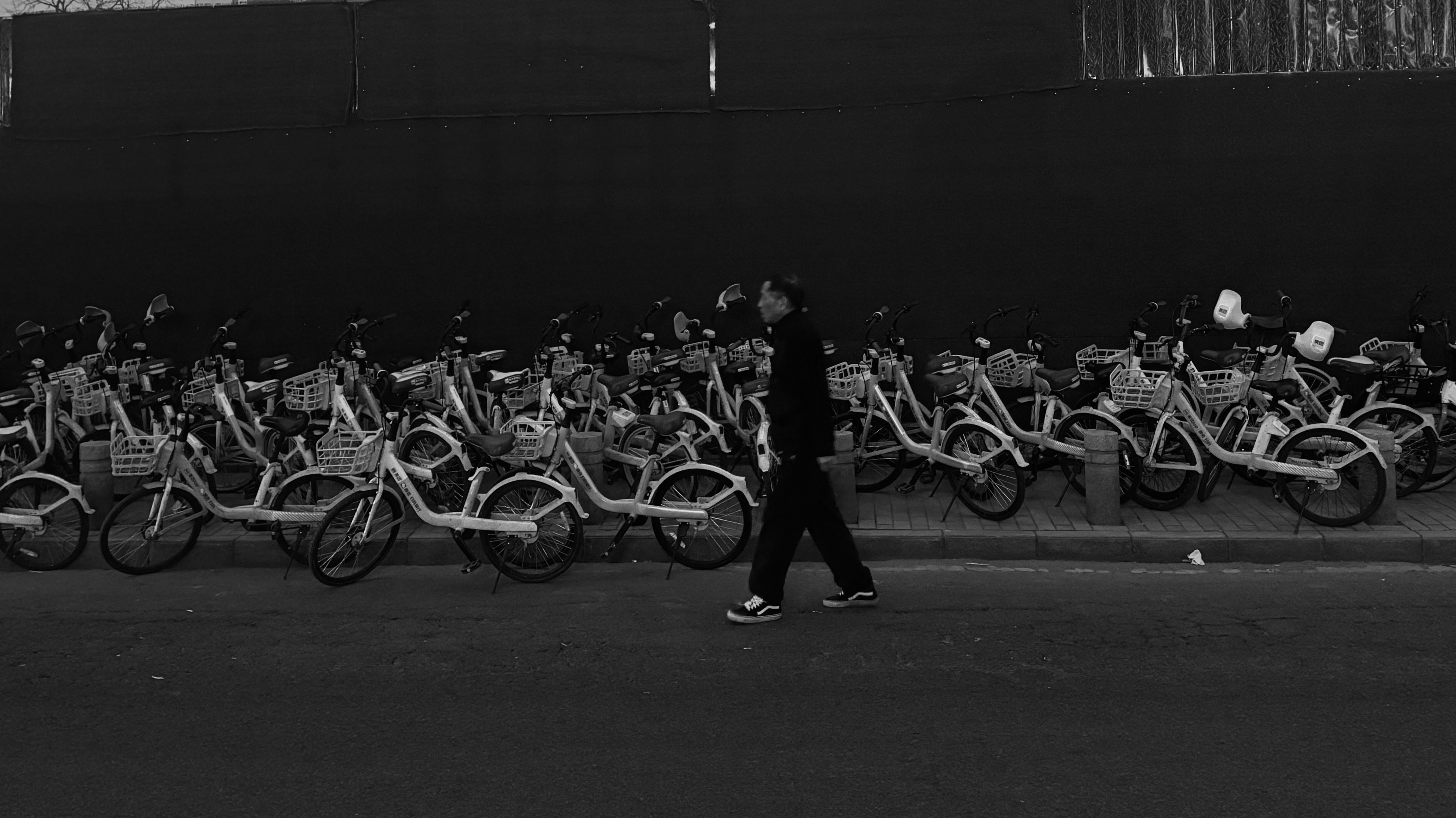 A person walks past a row of parked bicycles.