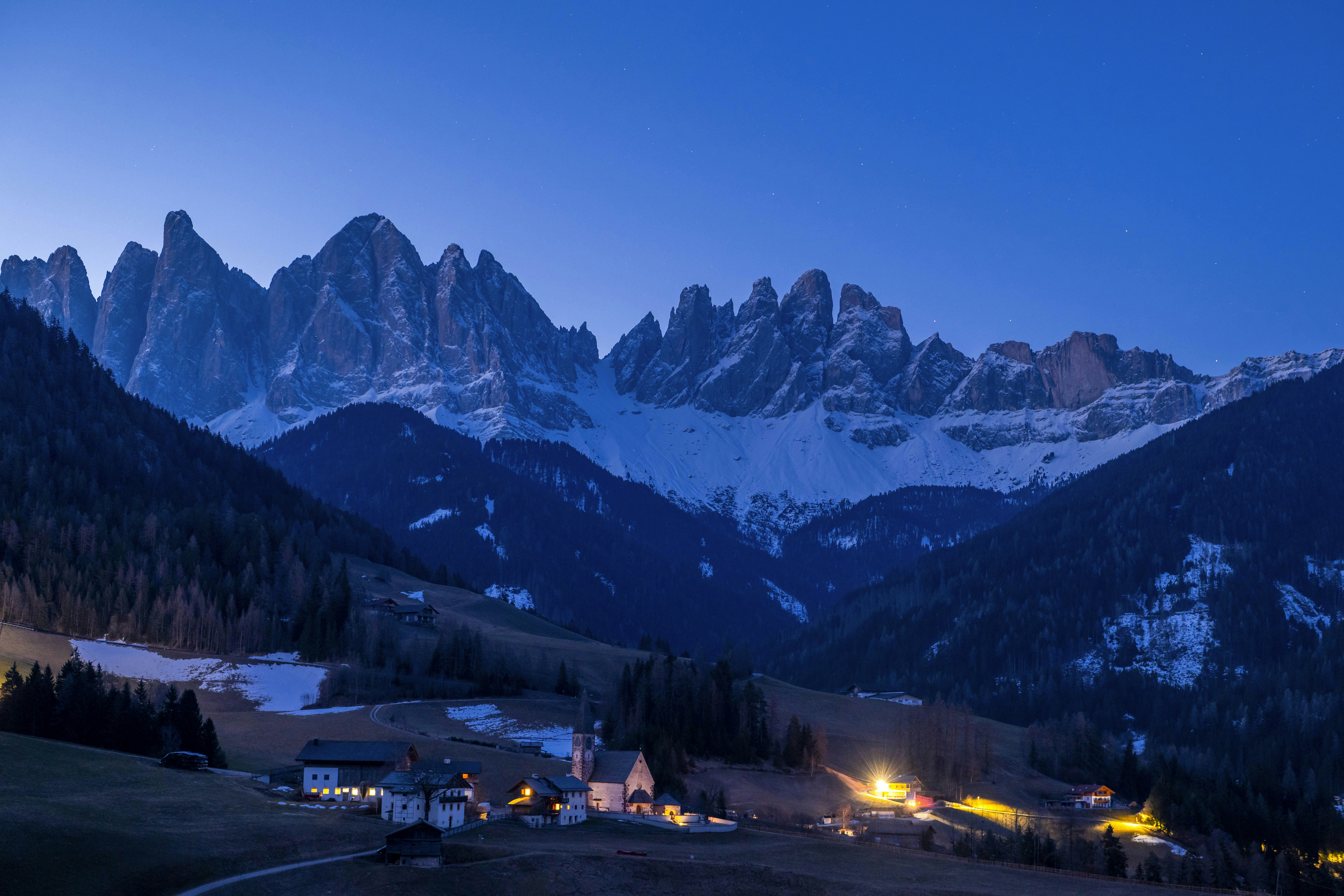 A small village nestled in a mountain valley at dusk.