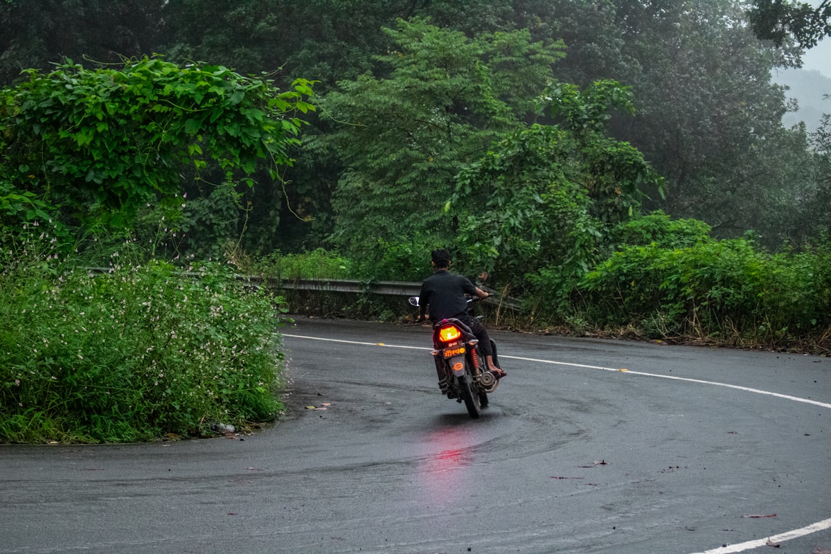 A motorcycle rider on a wet winding mountain road through mist