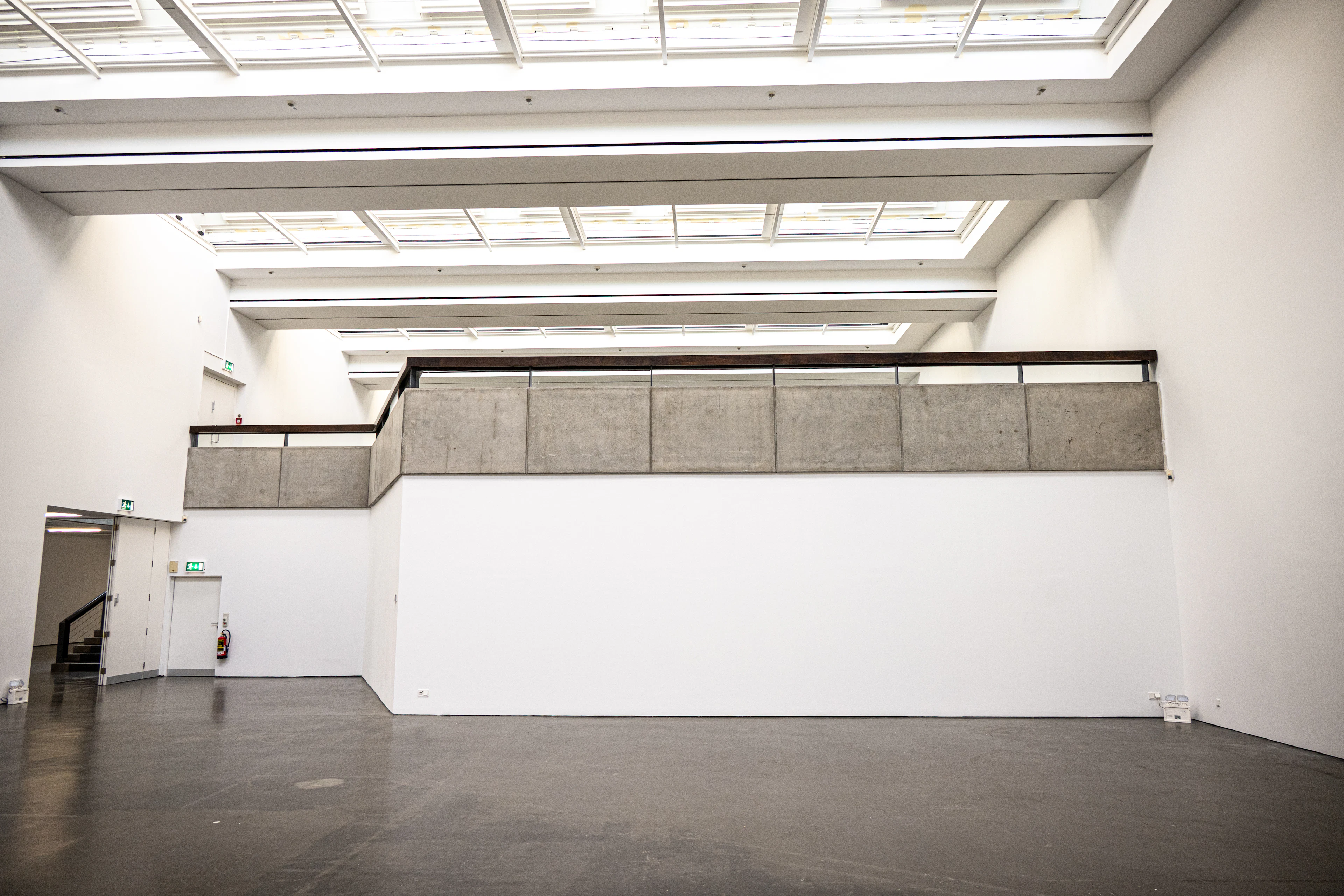 Modern gallery with white walls, a concrete floor and skylights