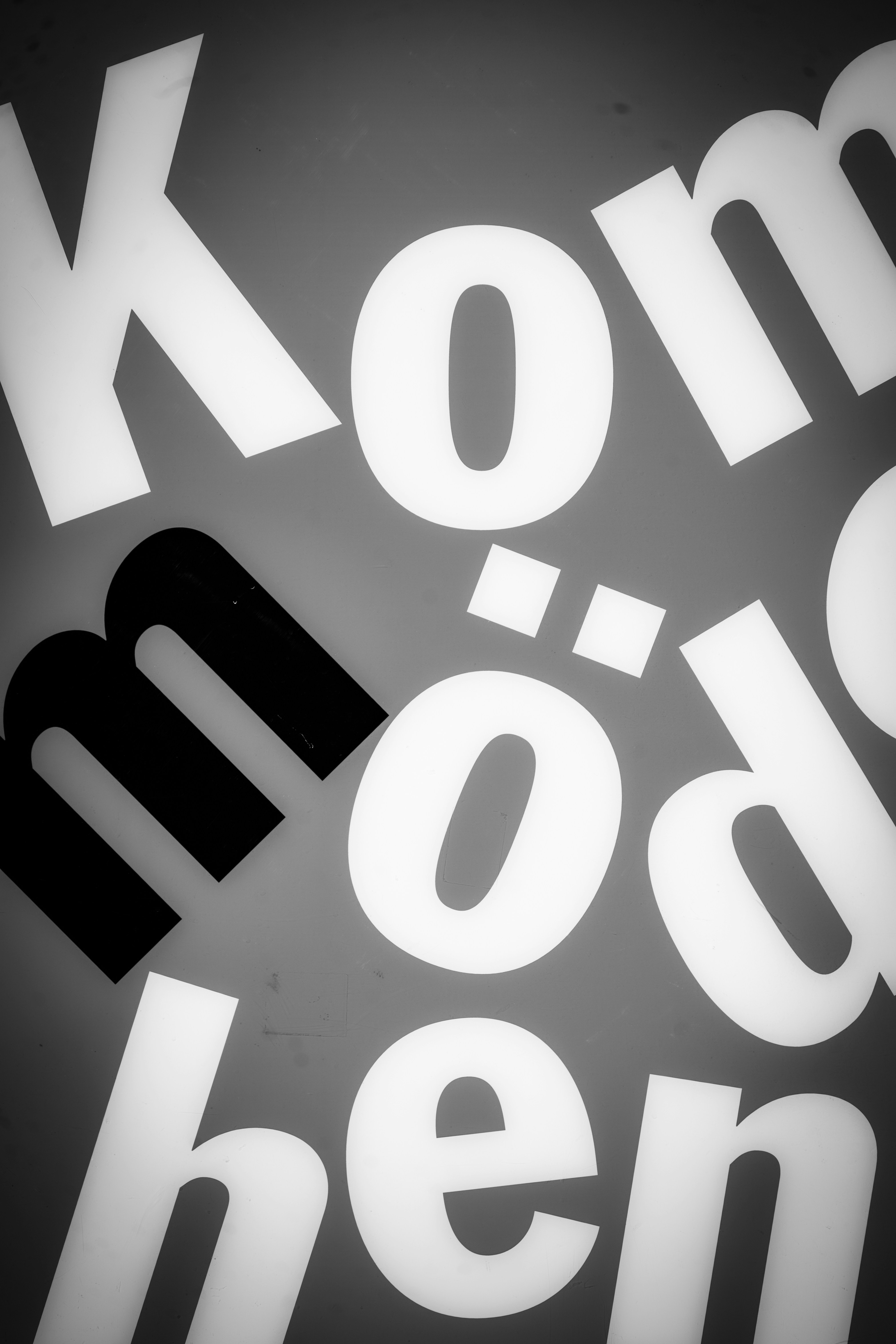 Close-up of the word "komödiensch" on a gray background.