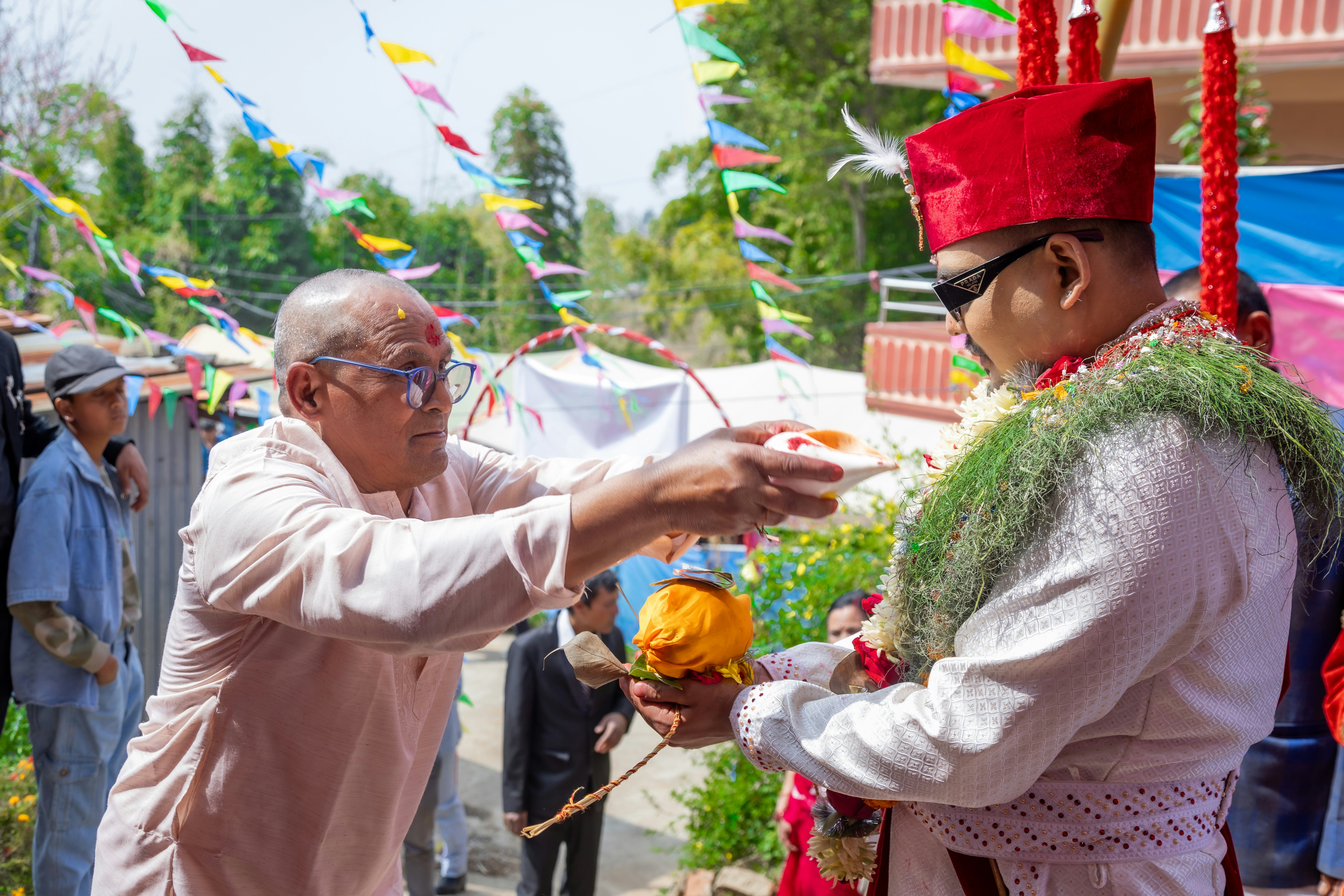 Man in traditional attire receives a ceremonial offering.
