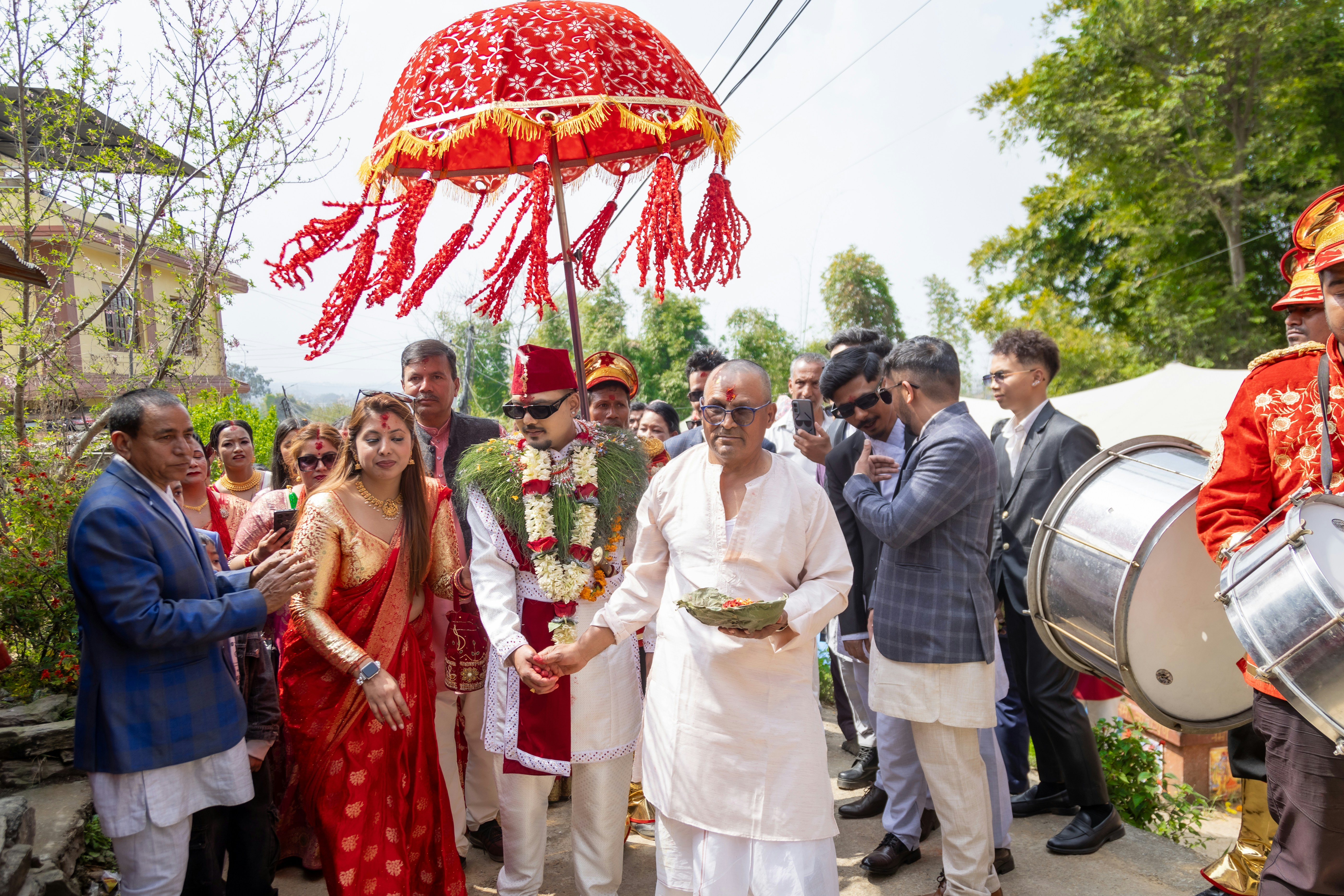 Une procession nuptiale avec un parapluie décoré et des musiciens.