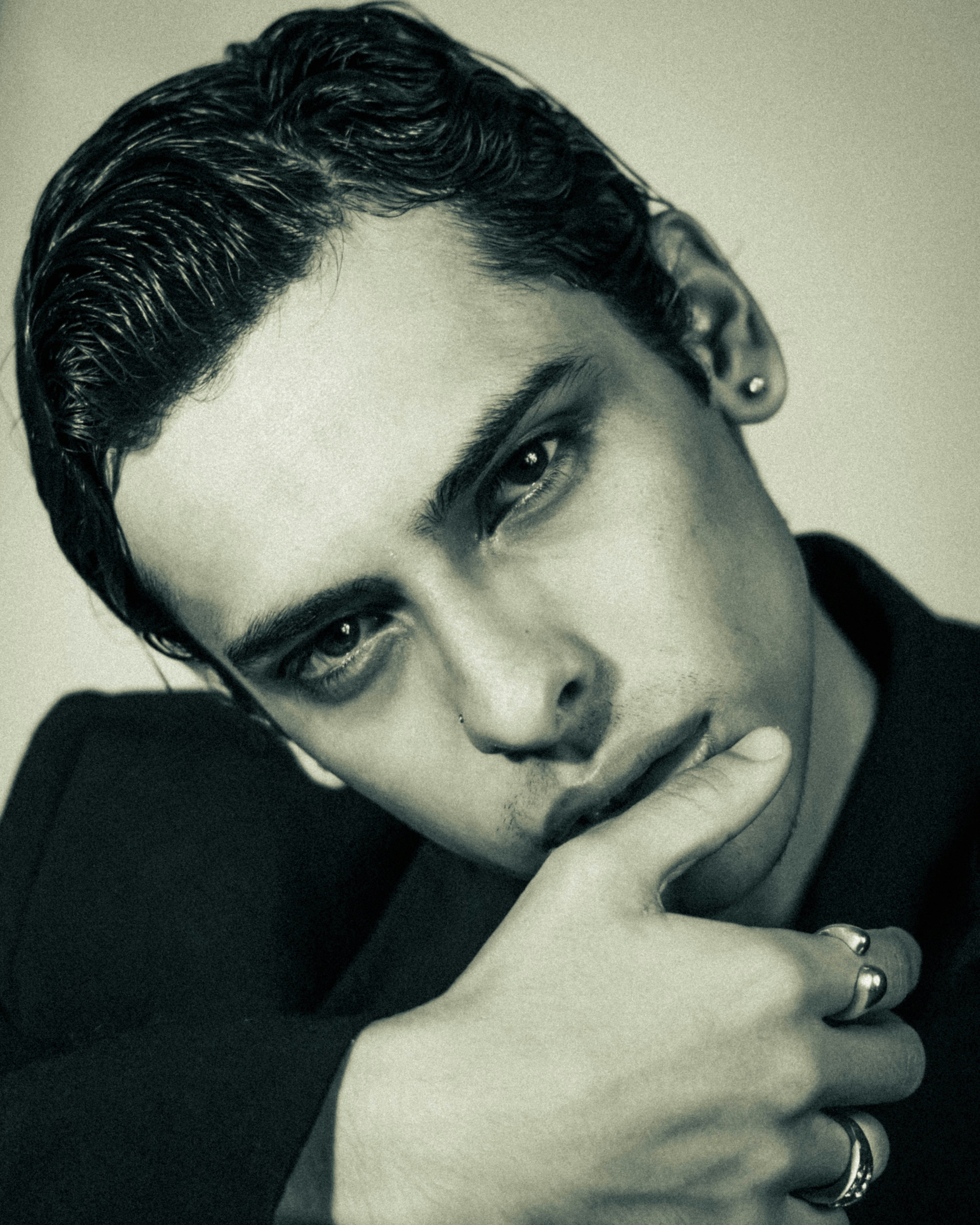 Ein Mann mit dunklem Haar und Ringen am Kinn